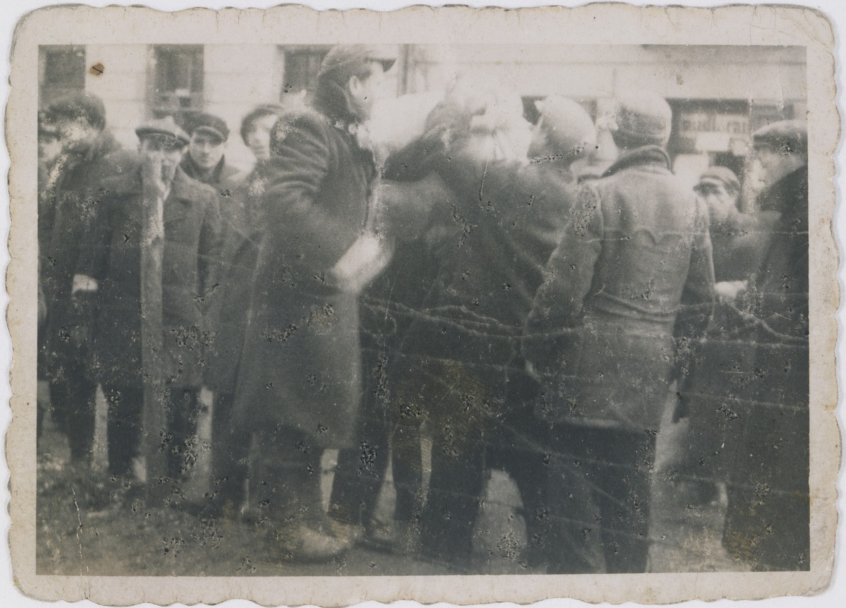 A Polish boy passes smuggled goods to Ajzyk Wierzbicki and Krawczyk in the Warsaw ghetto through a fence on Krochmalna Street.