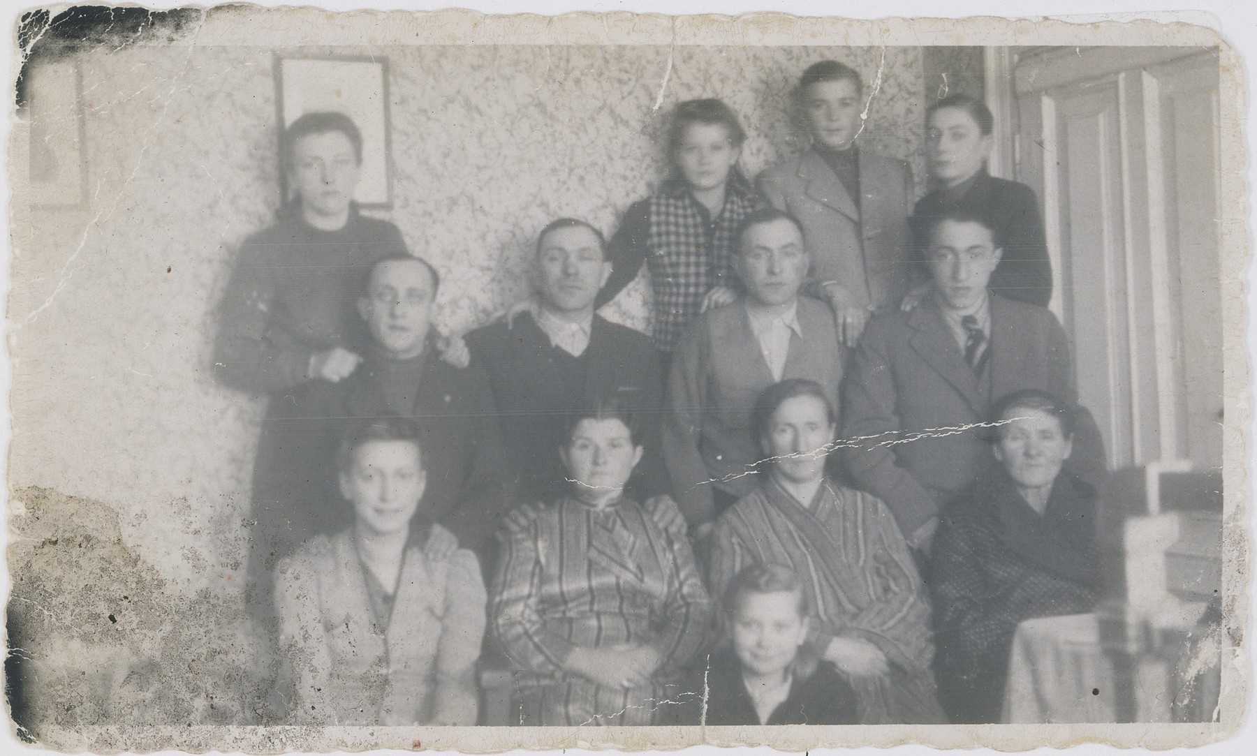 Portrait of the Wierzbicki and Kostanski families in the Warsaw ghetto.

Pictured in the center, front is Danusia.  In the front row from left to right are: Fela, Wladyslawa Wierzbicka, Berkowa, Grandma Bajla.  In the second row from the front, from left to right are: Szmulek, Ajzyk, Berek, Jakob.  In the top row from left to right are: Nacha, Jadzia, Jan and Nathan.