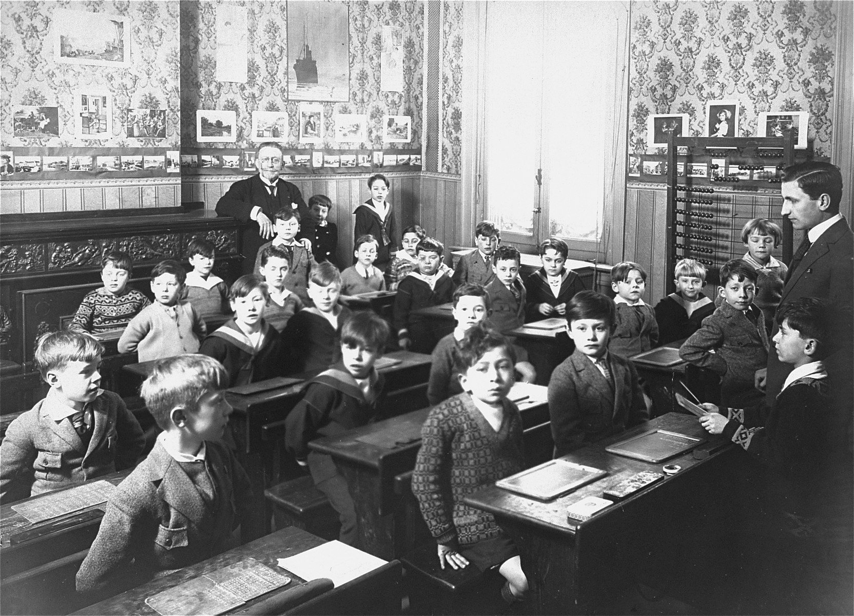 A young boy recites his lessons in a classroom in Antwerp, Belgium.

Among those pictured is Willem Friedman (seated in the middle row, second desk, left side).  Willem was born in 1919 in Holland, but from an early age lived in Belgium.