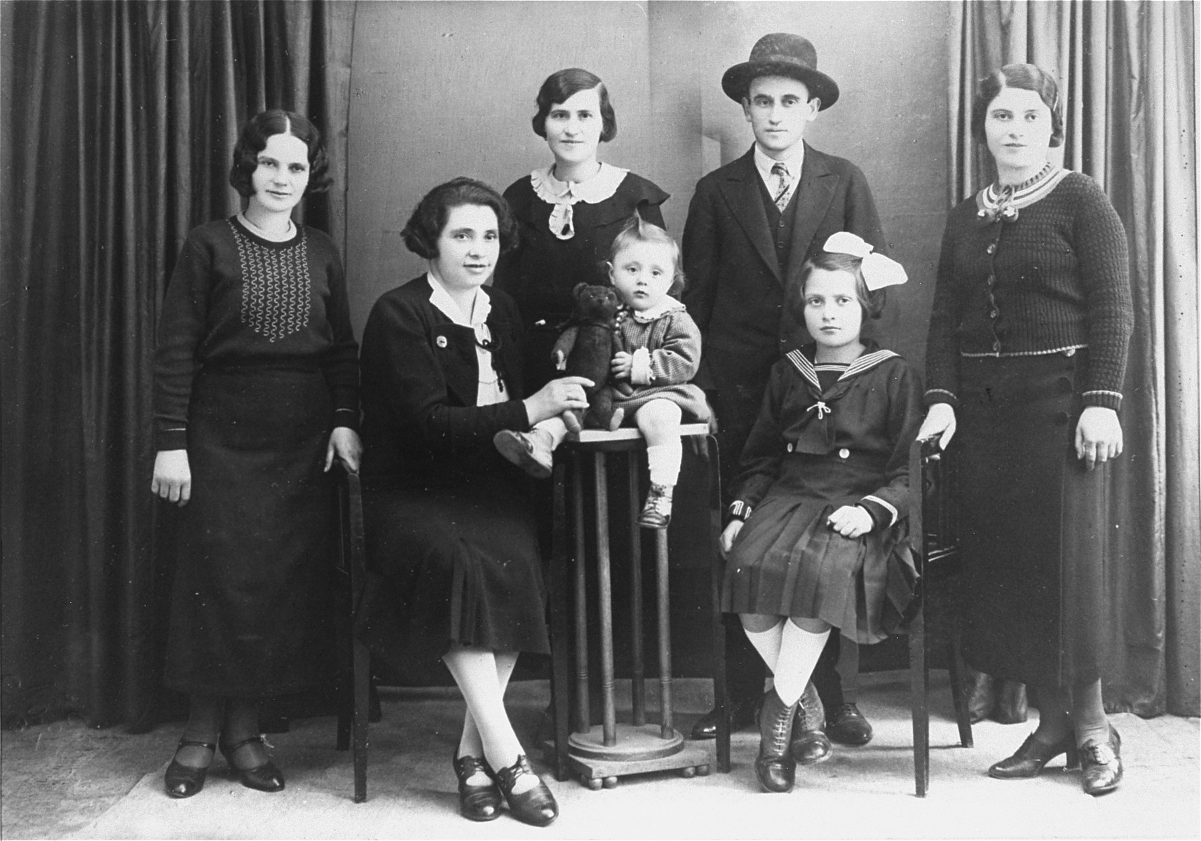 Studio portrait of the Englander family, taken on the eve of Lillian's emigration to the U.S.  

Pictured (from left to right) are: Rozi, Ettela (Adolph's wife), Anush (standing), Ali, (Adolph's youngest son); Magda (Adolph's daughter), Shlomi (standing) and Lillian Englander.  

Shlomi Englander died soon after this portrait was taken.  Rozi went into hiding with her niece, Magda.  She was caught in 1942 and deported to Poland.  Anush was killed in 1942, along with her husband and child.  Adolph and Ettela Englander, together with their two children, Ali and Magda, were deported to Auschwitz in 1944.  Only Magda survived.