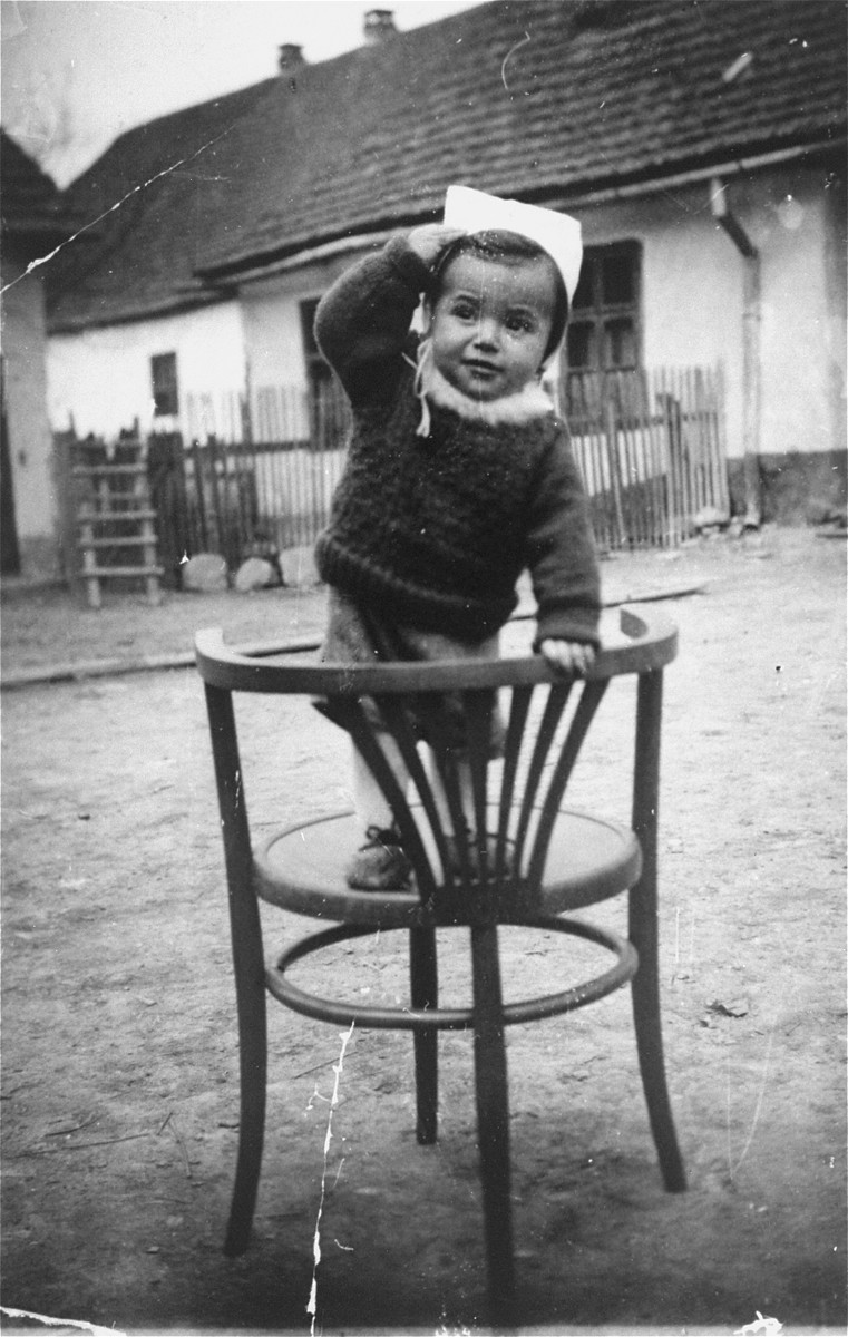 Portrait of a Jewish child standing outside on a chair.

Pictured is Chaim Hersh Kirschenbaum, son of Hanna and Ignatz Kirschenbaum.  Both he and his mother perished in Auschwitz.