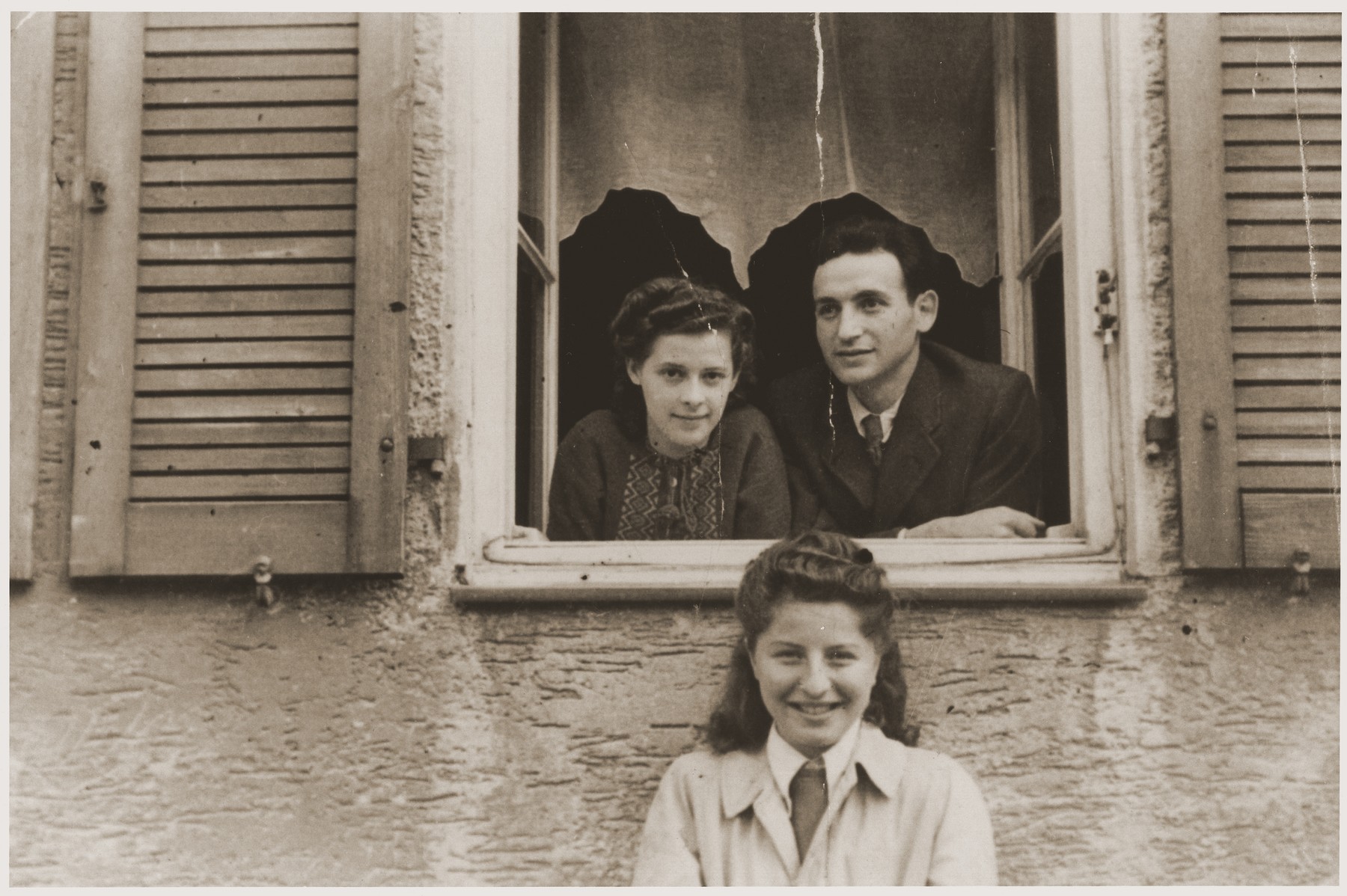 Hania Goldman (bottom) poses beneath a young couple, who are looking out the window of their room in the Fuerth displaced persons camp.