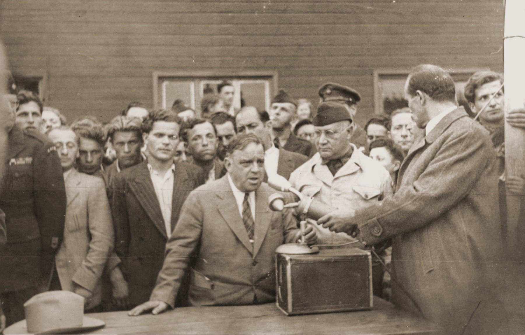 UNRRA Director General Fiorello LaGuardia delivers a speech at the Berlin-Schlachtensee displaced persons camp.  

Also pictured is UNRRA Schlachtensee camp director Harold Fishbein (standing next to LaGuardia on the right).