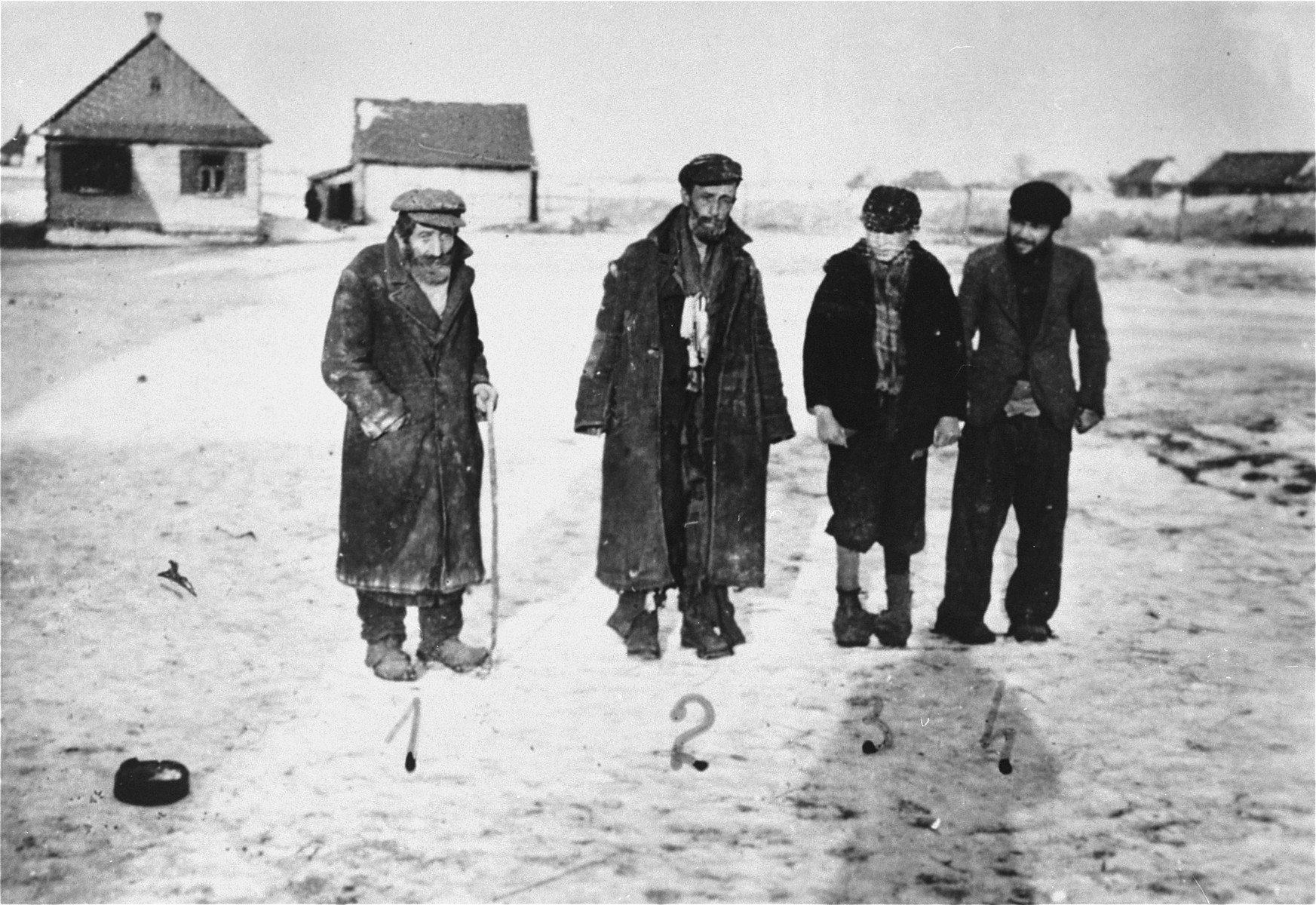 Four Jewish men pose on an unpaved road in the Wisznice ghetto.

Pictured from left to right are: Jeko Frydman, Zachary Bajmdzole, Pinkus Rozenberg and Moszko Kaszemadzer.