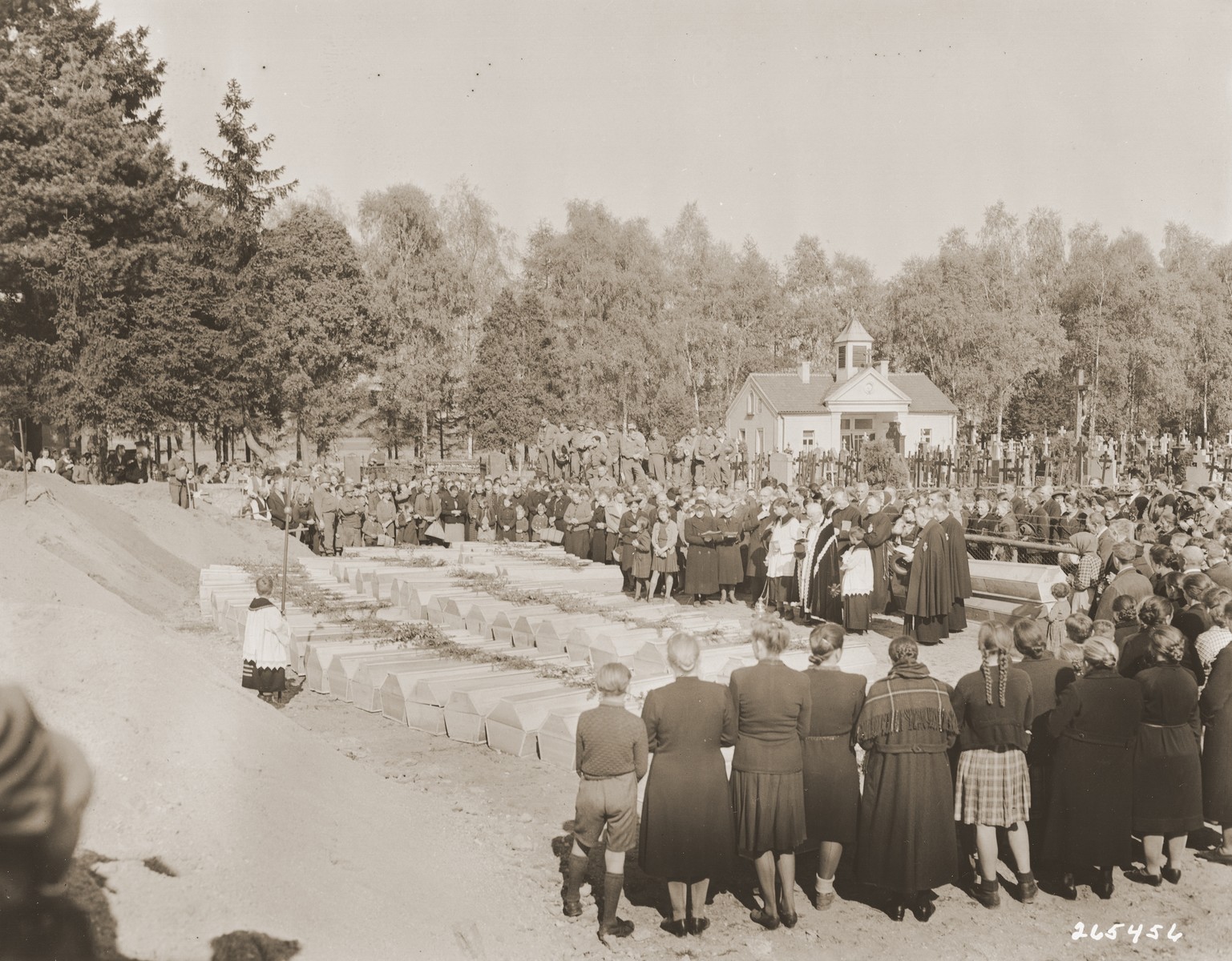 German civilians attend funeral services conducted by the pastor of Schwarzenfeld for the 140 Polish, Russian, and Hungarian Jews exhumed from a mass grave near the town.  

The victims died while on an evacuation transport from the Flossenbuerg concentration camp.