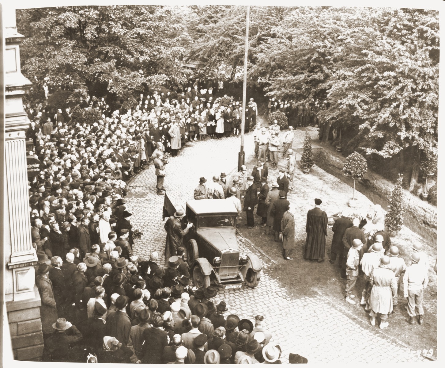 American soldiers and German civilians from Solingen-Ohligs attend funeral services for the 71 political prisoners, exhumed from a mass grave near the town, in front of the city hall.  

The victims, most of whom were taken from Luettringhausen prison, were shot and buried by the Gestapo following orders to eliminate all Reich enemies just before the end of the war.