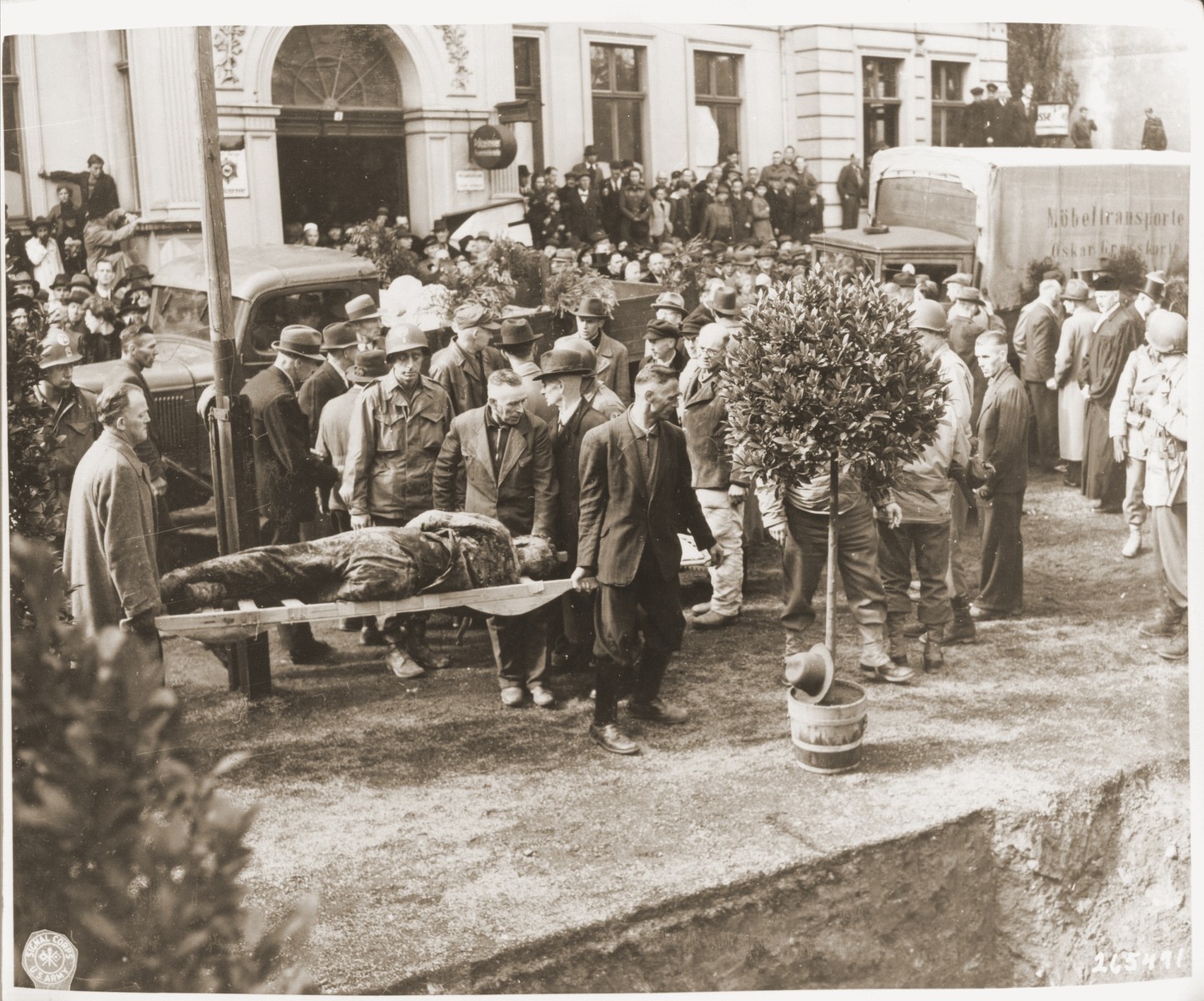 Under the supervision of American soldiers, German civilians bury the bodies of 71 political prisoners, exhumed from a mass grave near Solingen-Ohligs, in front of the city hall.  The victims, most of whom were taken from Luettringhausen prison, were shot and buried by the Gestapo following orders to eliminate all Reich enemies just before the end of the war.