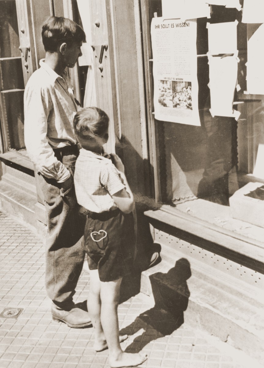 Two German boys  rom Possneck read a poster put up by the U.S. Army entitled "You Should Know About It!" which describes atrocities committed in concentration camps.

Original caption:
"GERMAN BOYS VIEW HORROR CAMP PICTURES
German boys in Possneck, Germany, read a poster June 18, 1945, describing atrocities committed by the Germans in concentration camps. Allied authorities in Germany are posting descriptions of these "horror" camps in town and villages, and requiring German civilians to read them."