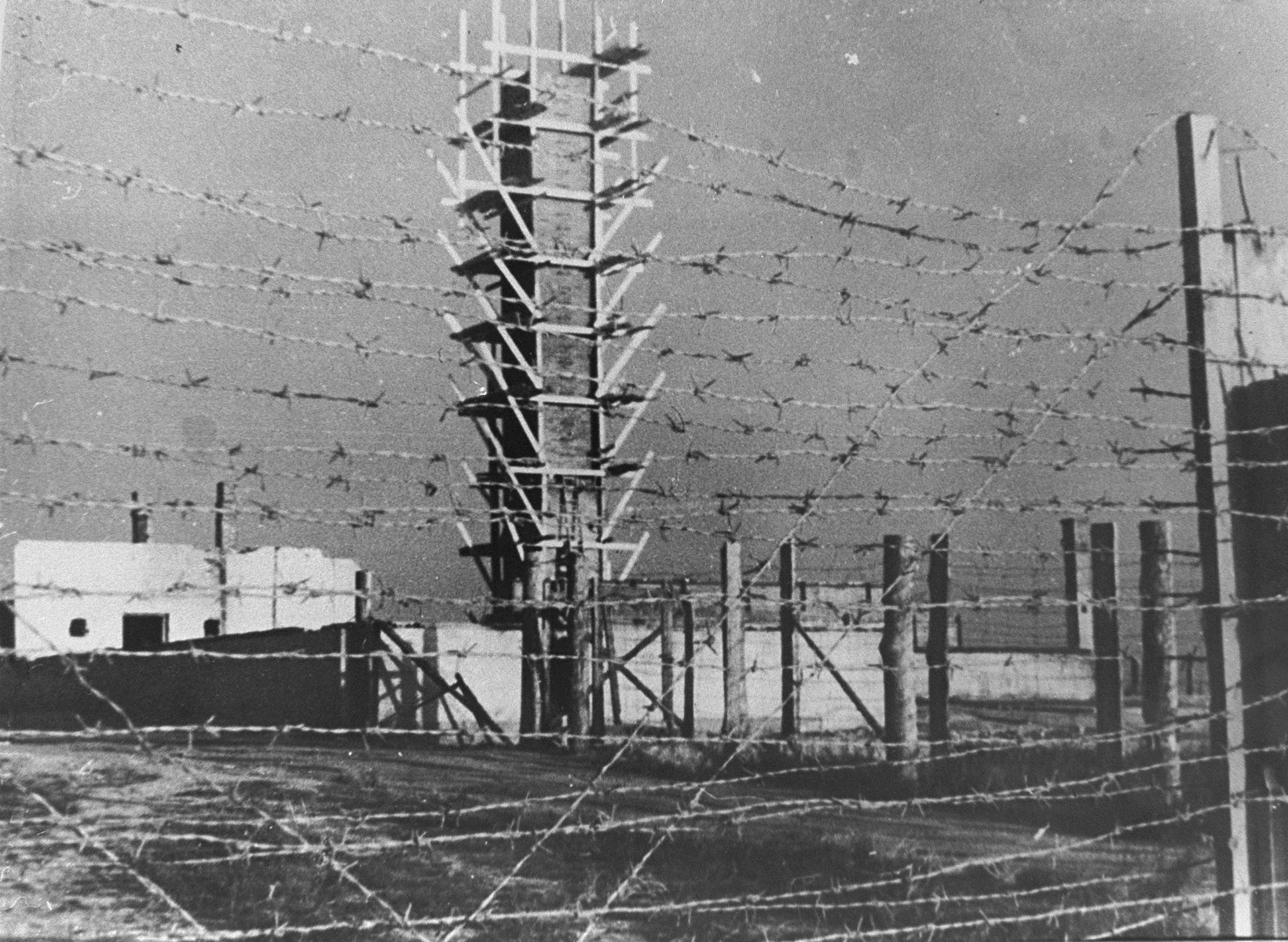 Postwar view of the crematoria and gas chamber in Majdanek through the barbed wire fence.