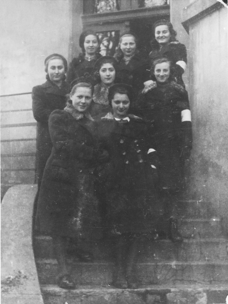 A group of Jewish teenage girls wearing armbands pose on the stairs outside a building in Bedzin.

Among those pictured is Chana Szlezyngier (front row center) and Tosia Szwajcer, the only one of the group to survive.