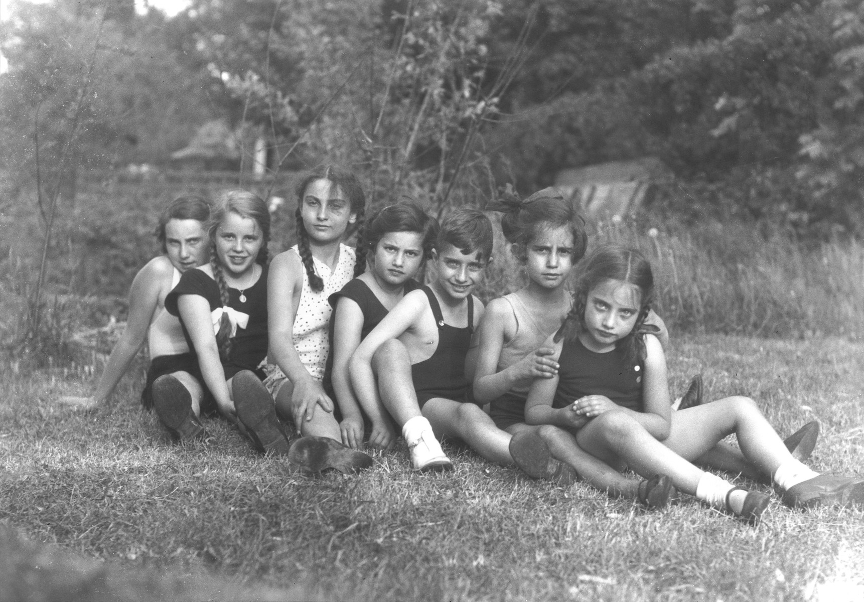 The children of Georg and Gertrude Anker sit in a row on the grass with their friends and cousins.

Pictured are Eva, Dodi and Hilde Anker, their cousins Heinz and Else Karplus, and two friends.