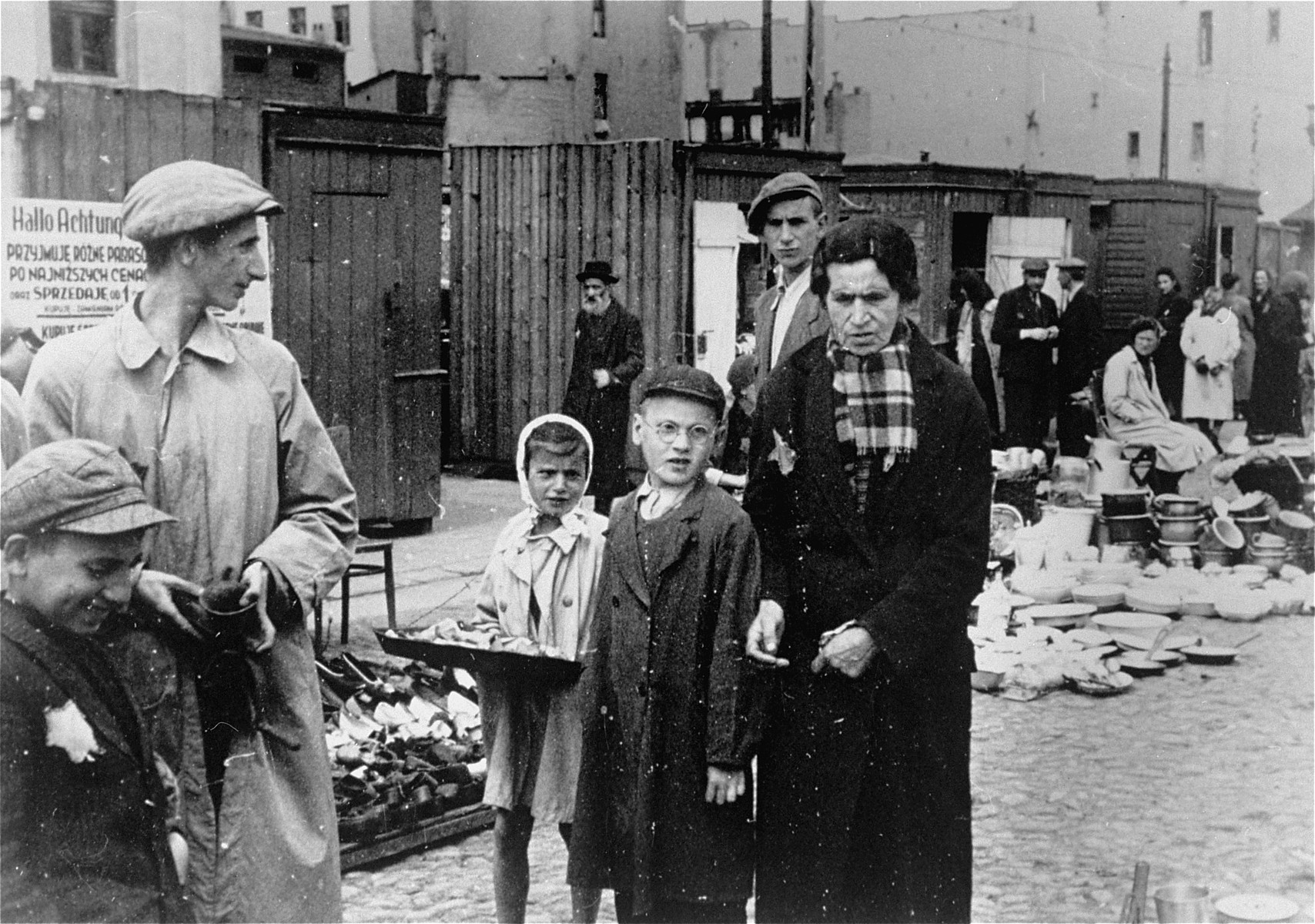 People at the outdoor market in the Lodz ghetto.  A child vendor carries her wares in a tray slung around her neck.