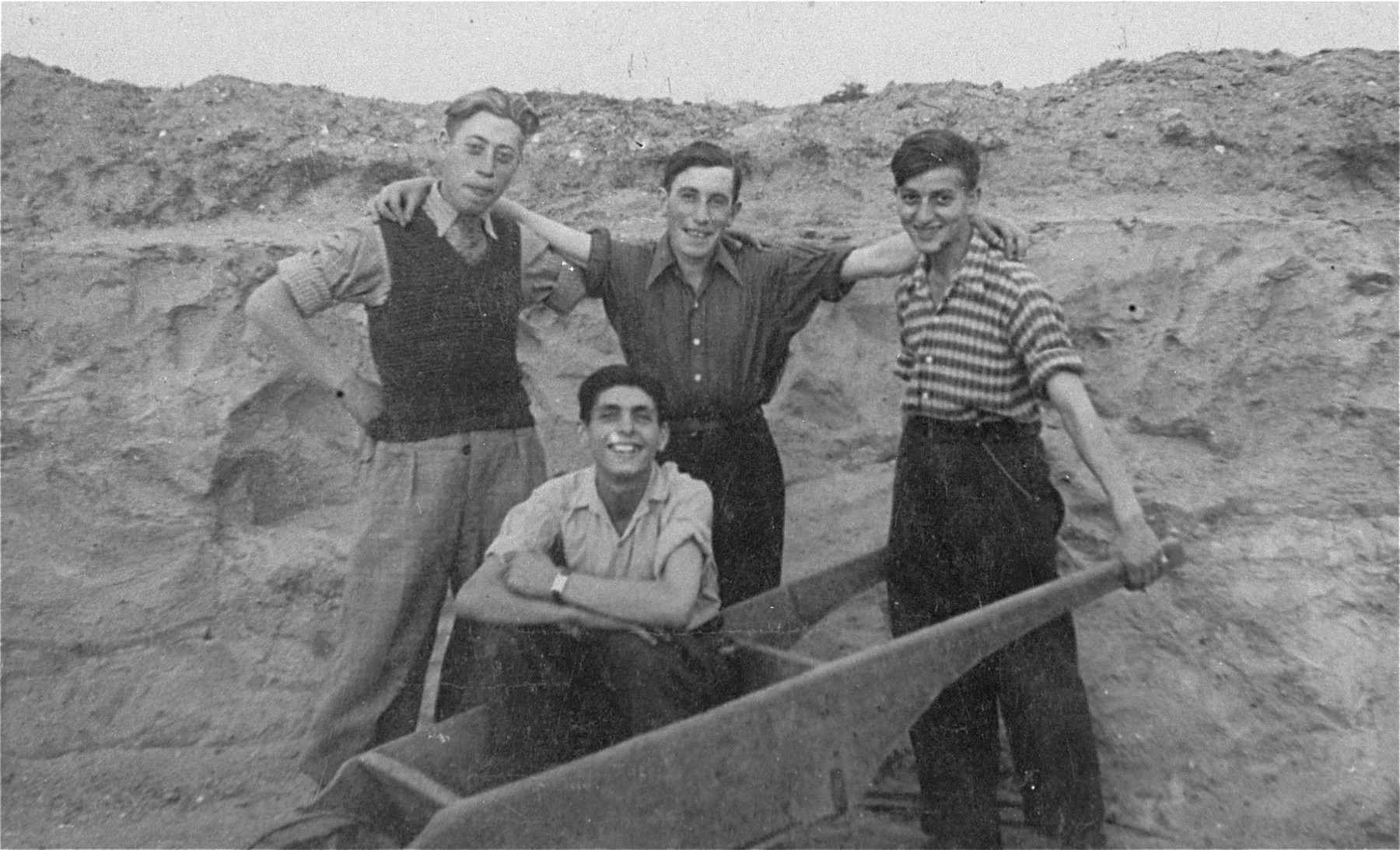 Four members of the Gordonia Zionist youth movement pose in a field in the Marysin quarter of the Lodz ghetto. 

Pictured standing from left to right are: Israel Weinberg, Shlomo Flam and Ariel Schwartz; sitting in the wheelbarrow is Menachem Fogel (who later perished).