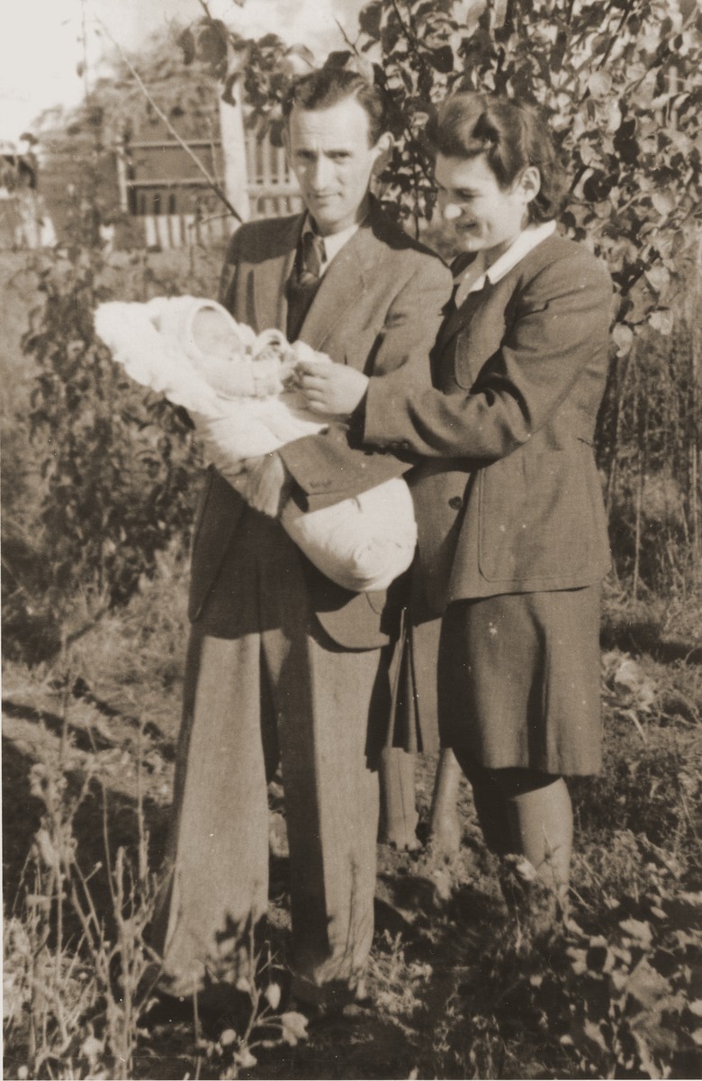 A young Jewish DP couple pose outside with their newborn daughter in the Fuerth displaced persons camp.  

Pictured are Henryk and Eugenia (Hochberg) Lanceter with their infant, Dina.