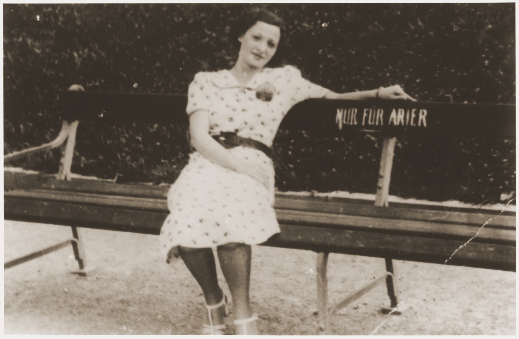 Lizi Rosenfeld, a friend of the Spitzers, sits on a park bench with a sign "Only for Aryans."