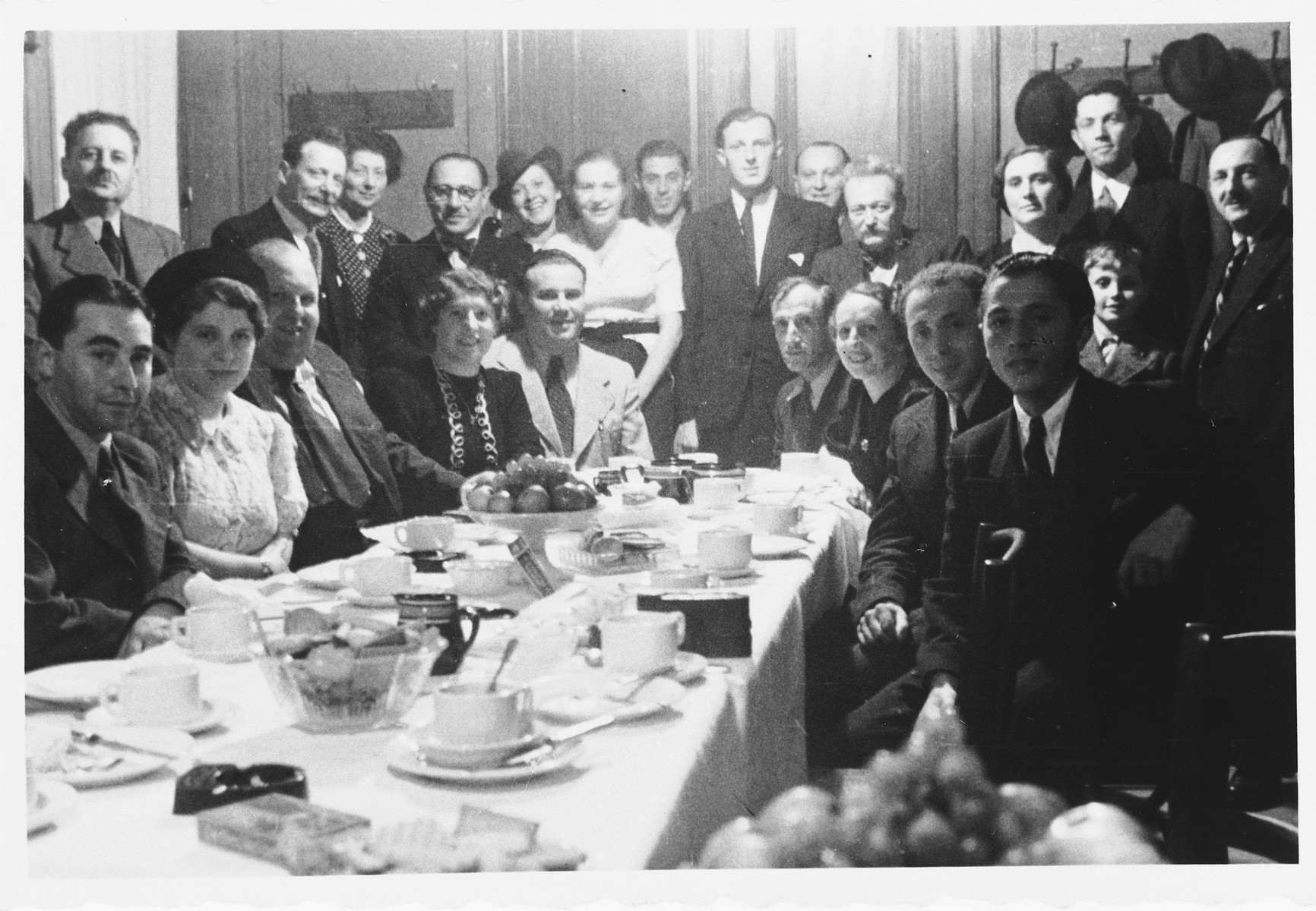 Members of the Luxembourg Jewish community pose with Jewish refugees from the Third Reich around a long dining table at a gathering sponsored by the ESRA Jewish social welfare organization.