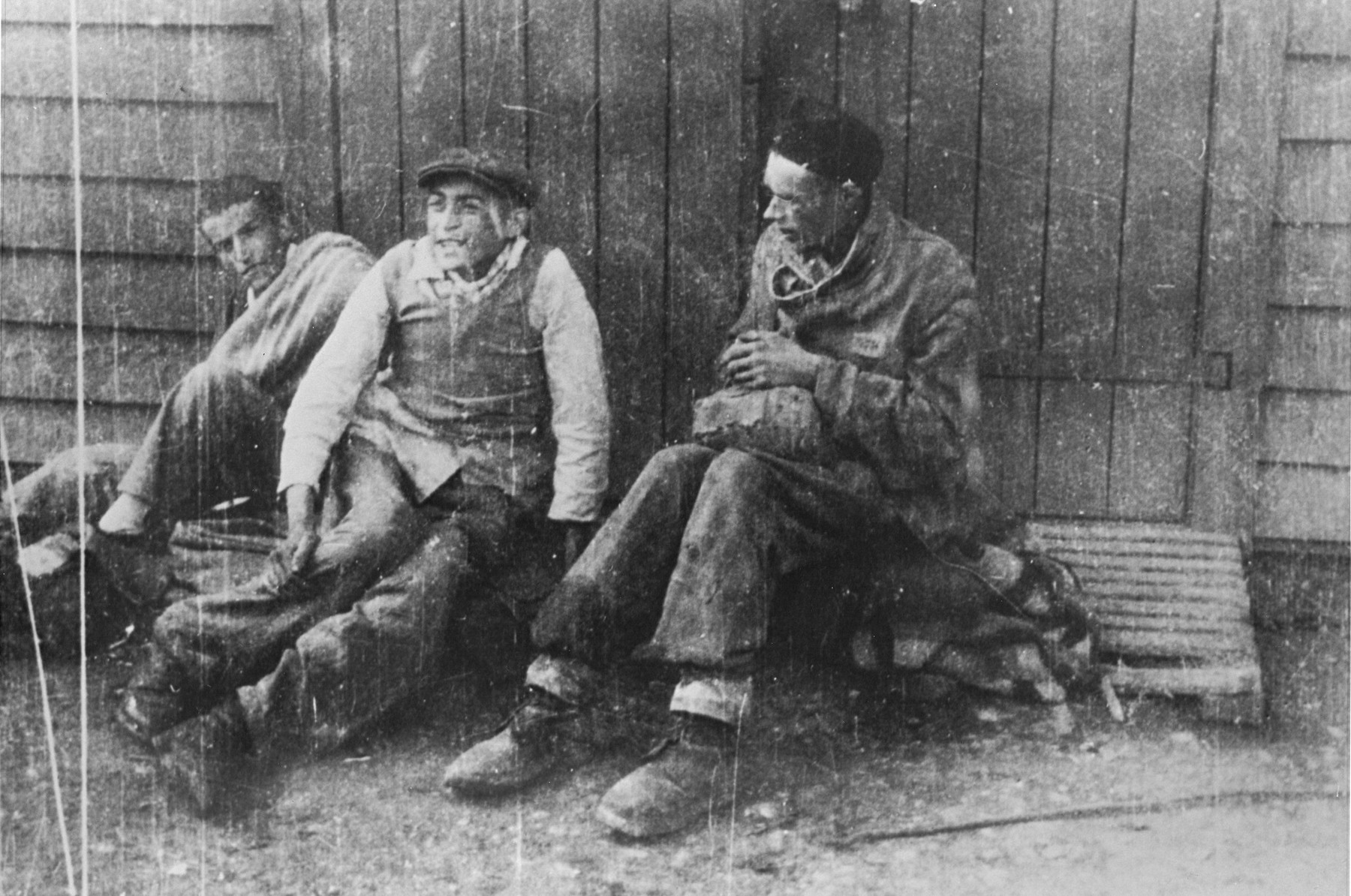 Three survivors sit outside a barracks in the newly liberated Hurlach concentration camp.

These men survived by hiding under a brick building when SS guards razed several barracks in the camp.  Only twelve survivors were found in Hurlach at the time of its liberation.