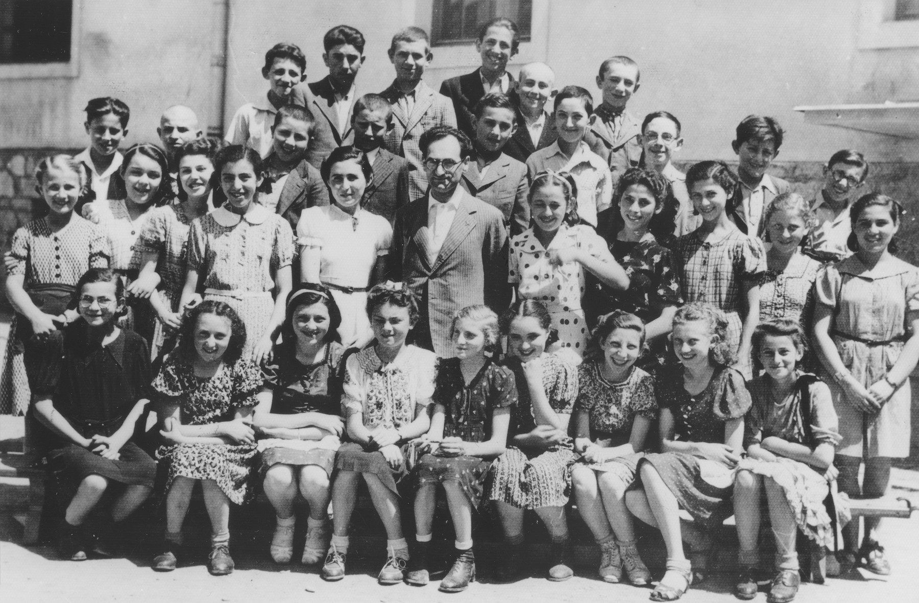 Group portrait of Jewish high school students at the Hebrew gymnasium in Mukachevo.  

Those pictured include Schweiger, Hilda Reinhartz, Pickholz, Jolanka Schwartz, Olga Seidenfeld, Eva Szegal, Miriam Katz, Ibolya Jakubovics, Schweiger, Rivka Graber, Judith Baumohl, Mignon Gottesman, Vera Hausman, Edith Feldman, Jeno Morvai (the principal and the art teacher), Eva Braun, Rose Honig, Szeren Weingarten, Trudy Kallus, Szidi Amzel, Bela Filipovics, Miki Haberman, Pali Littman, Bela Grunbaum, Mishu Berger, Menyus Pollak, David Stern, Josef Seidenfeld, and Aron Schwartz.