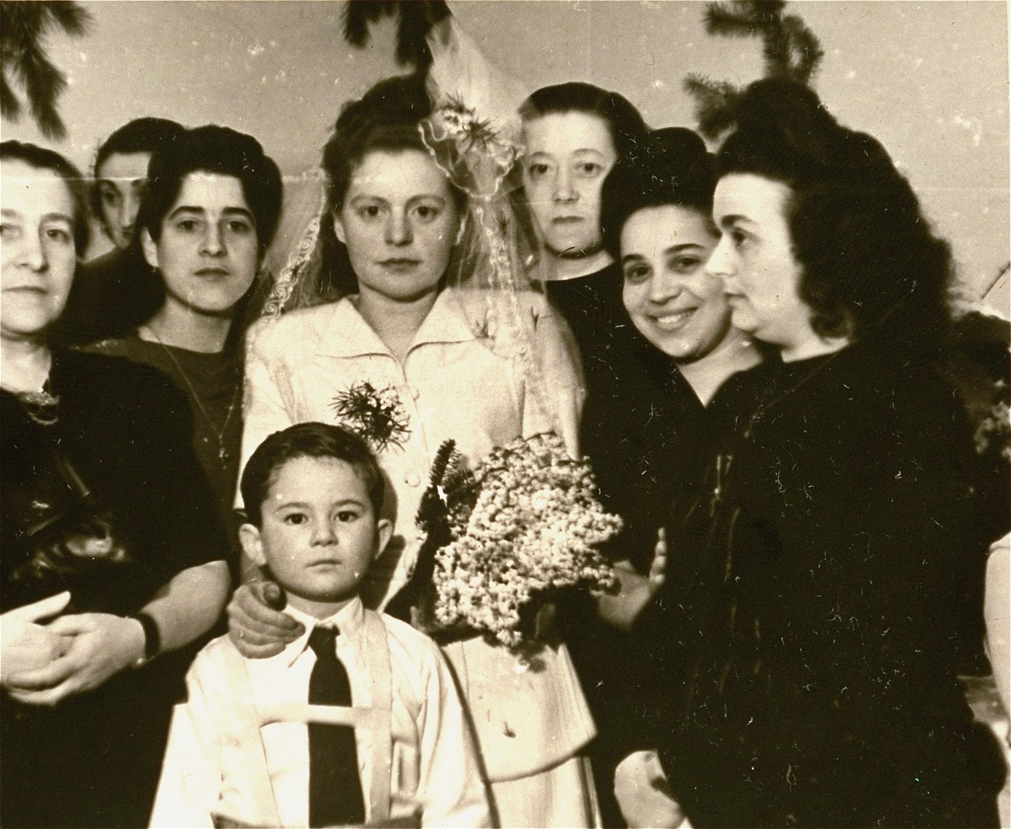 Group portrait of the Mandelbaum wedding party at the Bergen-Belsen displaced persons camp.  

Among those pictured are Jurek Kaiser (the child); Lola Mandelbaum (the bride) and Mania Zaks (second from the right).