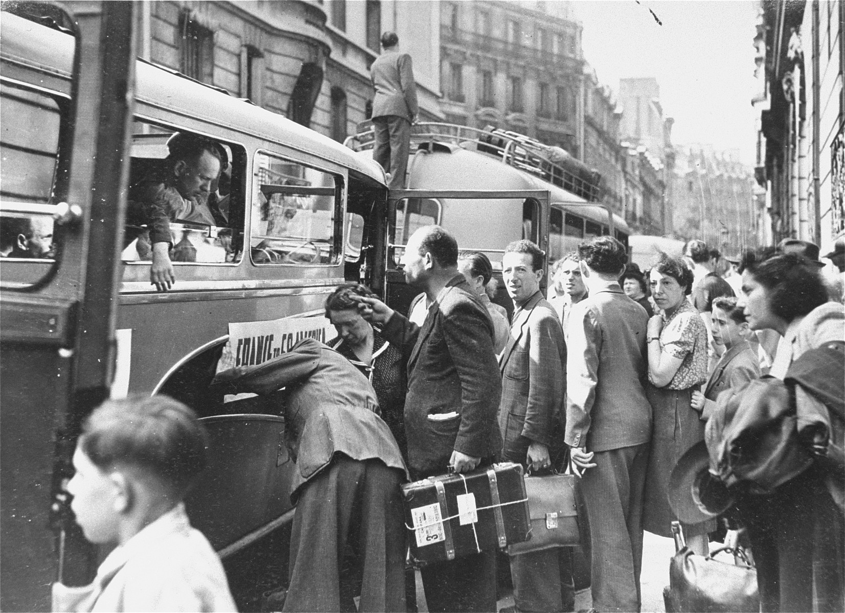 Jewish DPs wait in line on a street in Paris to board a convoy of buses that will transport them to Marseilles, on the first leg of their journey to new homes in South America and Australia.