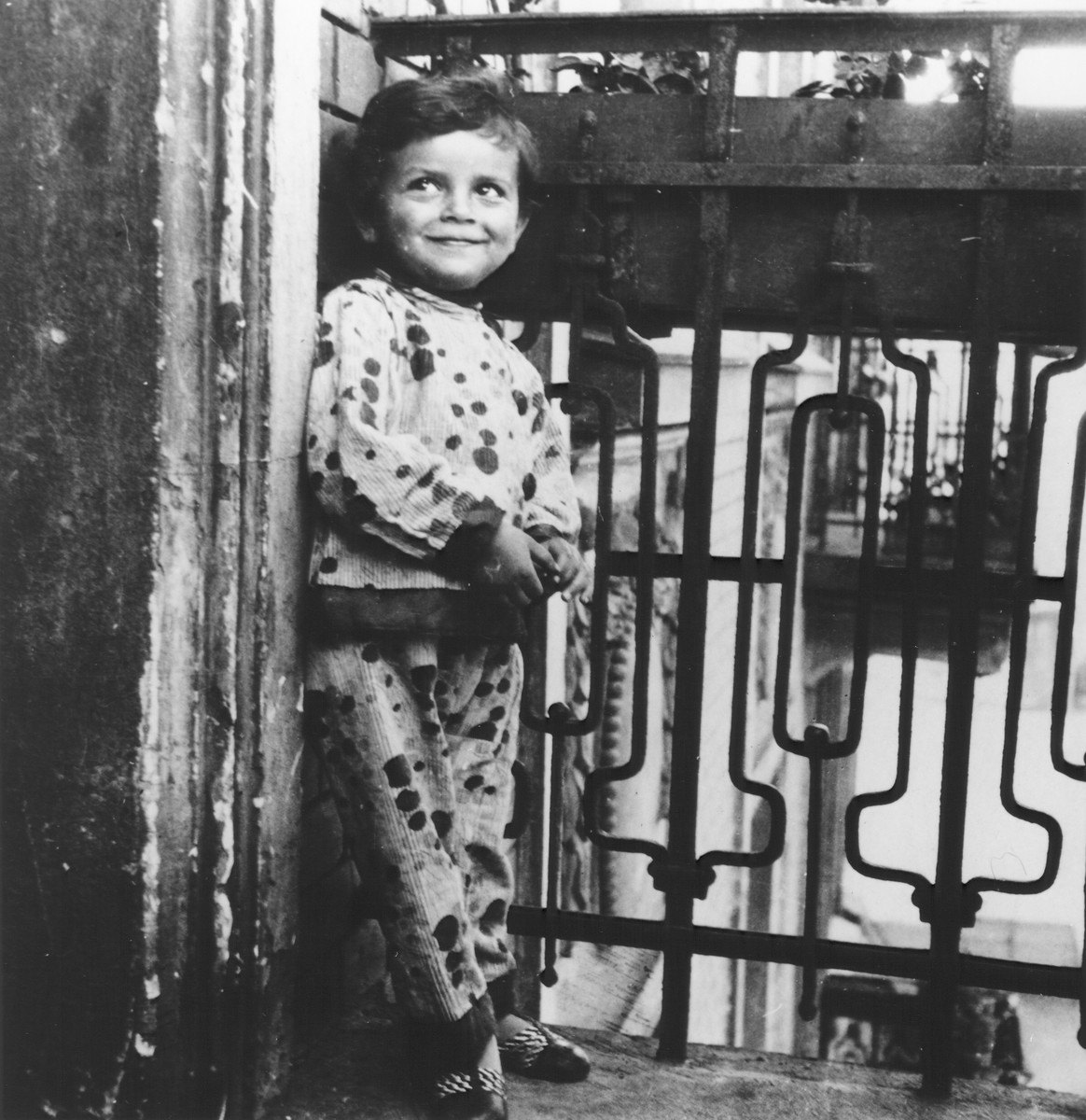 A young girl leans against the railing of the balcony of her apartment.

Pictured is the cousin of the donor.  Her father Shlomo was the younger brother of Joseph Halter.