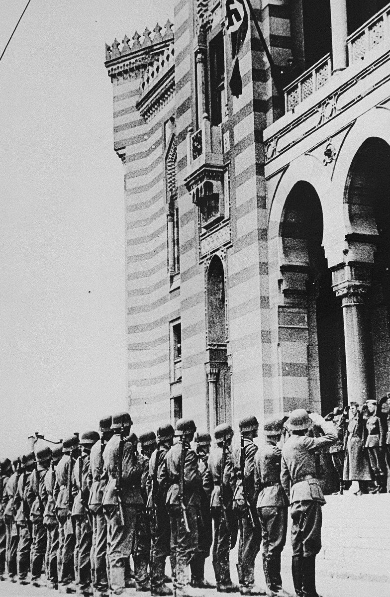 German troops salute during a flag raising ceremony on the balcony of Sarajevo city hall.