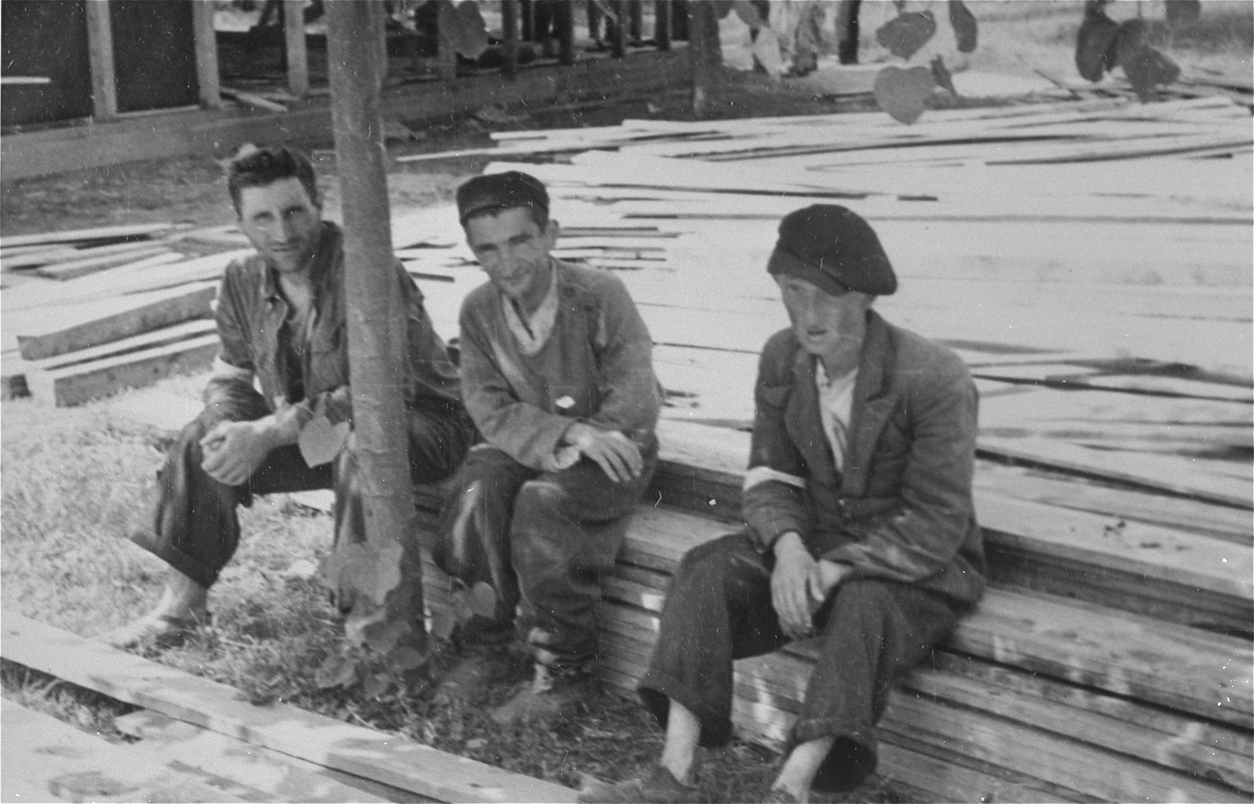 Three Jewish men who have been conscripted for forced labor, sit on a pile of lumber in Konskowola.