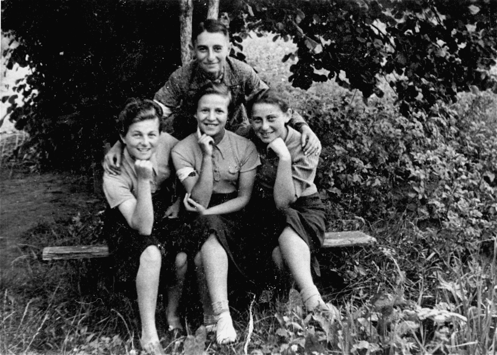 Four Jewish teenagers wearing armbands pose outside on a bench in the Konskie ghetto.

Among those pictured are Herman Neudorf and a friend named Jadzia (sitting, left).