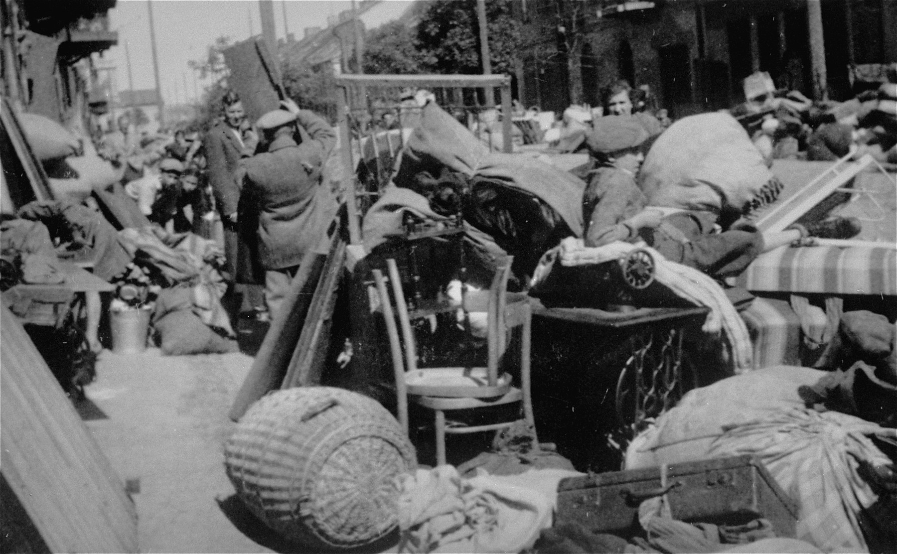 Piles of furniture and household belongings of Jews who are being transferred to the ghetto cover the pavement of a street in Kutno.

The original German caption reads: "Evacuation of Kutno. Jews out!"