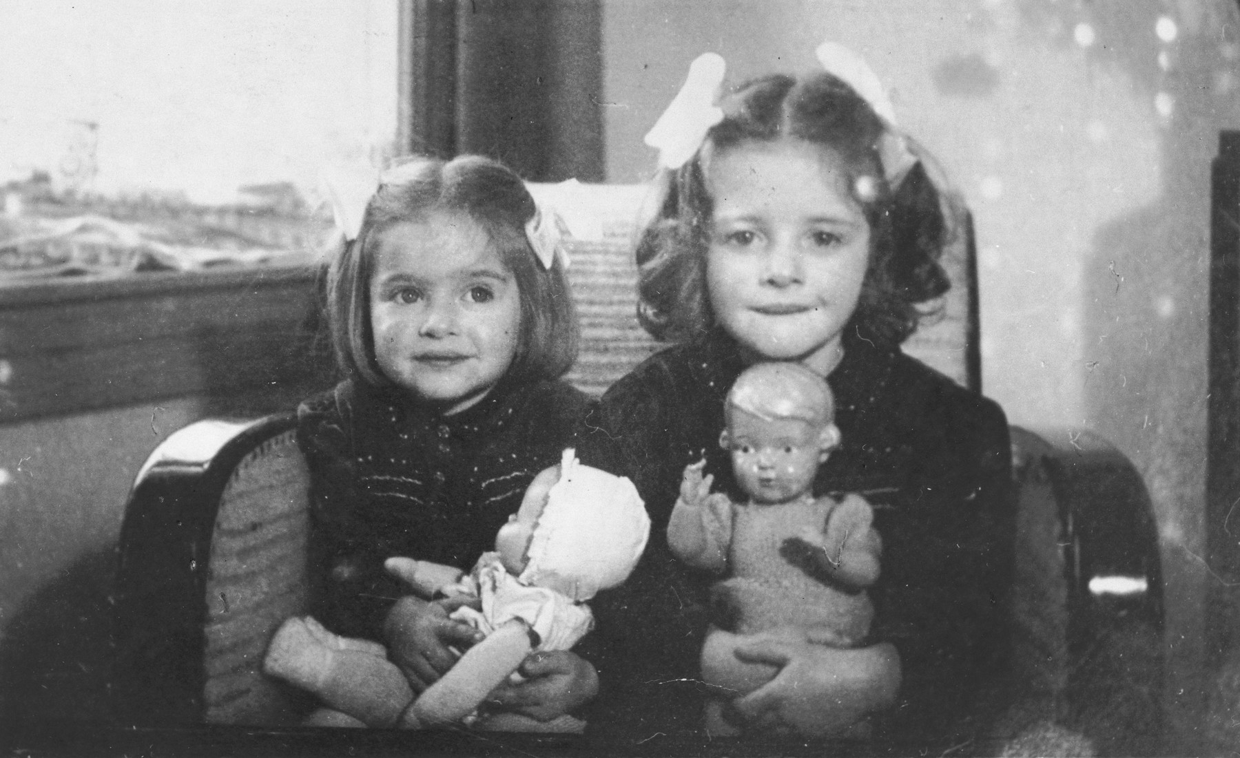 Two Jewish sisters pose with their dolls in their home in The Hague.

Pictured are Eva (right) and Leana (left) Münzer.  Both later perished in Auschwitz.