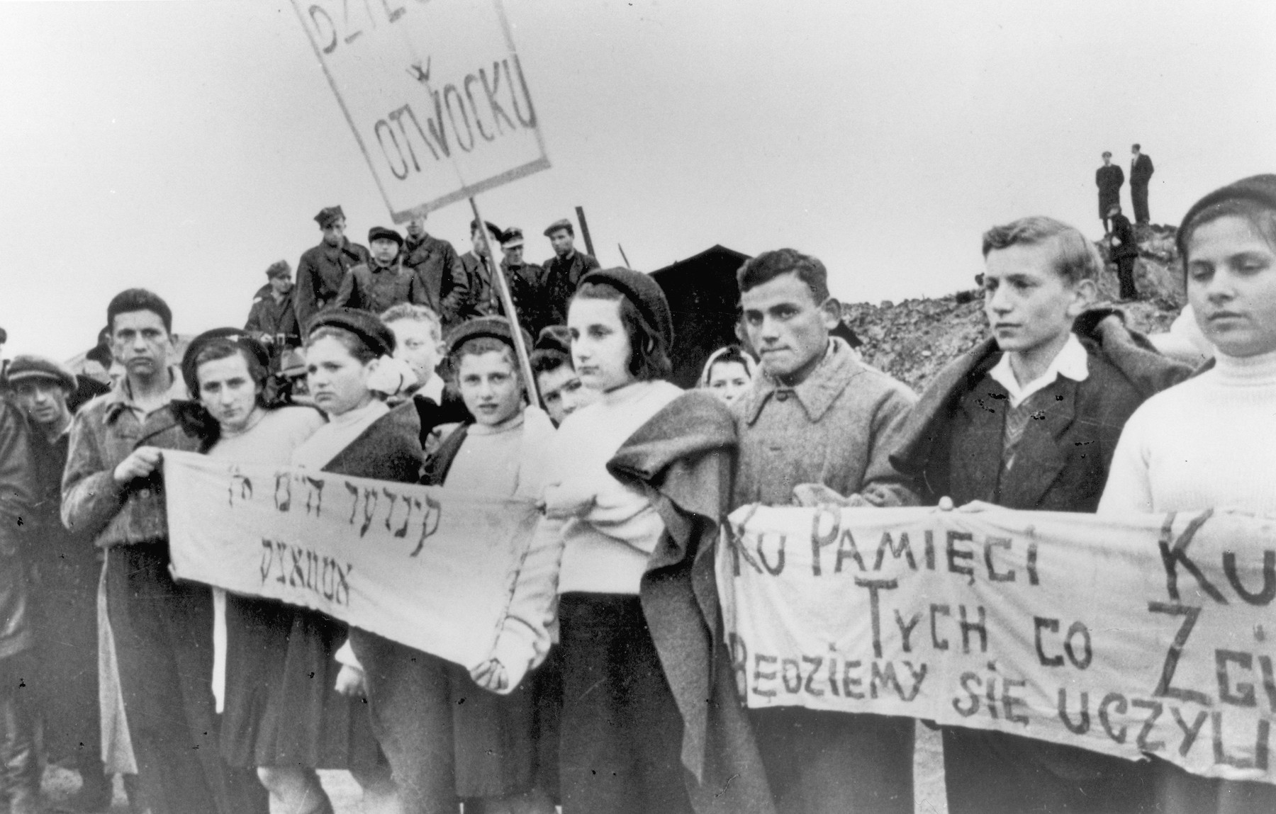 Jewish children from Otwock carrying signs and banners attend a demonstration [probably to mark the fourth anniversary of the Warsaw ghetto uprising].
