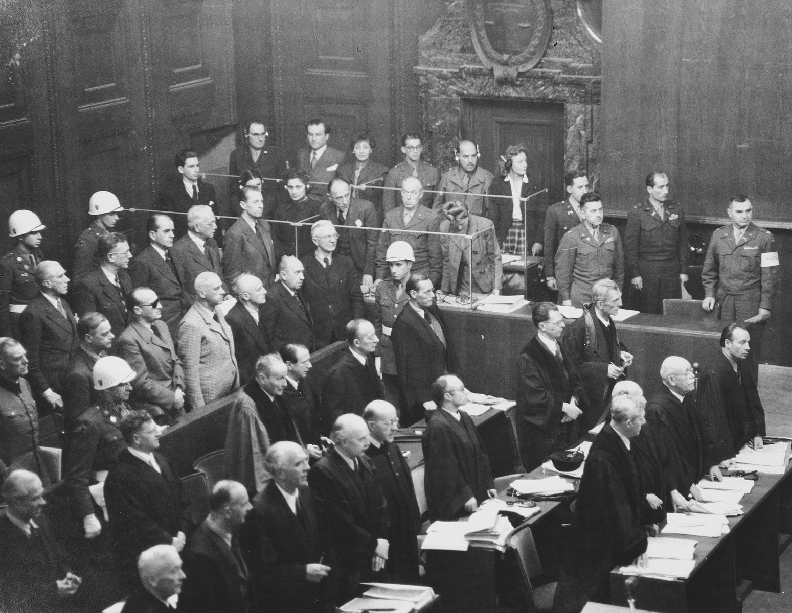 The defendants and defense attorneys stand in their places at a session of the International Military Tribunal trial of war criminals at Nuremberg.