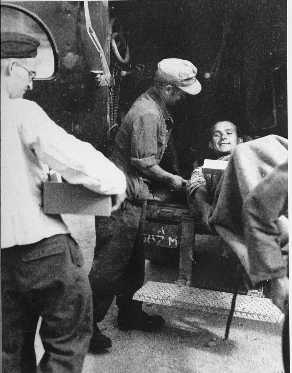 A survivor from Ebensee is loaded onto an ambulance by German military personnel for transportation to the 139th Evacuation Hospital for medical treatment.