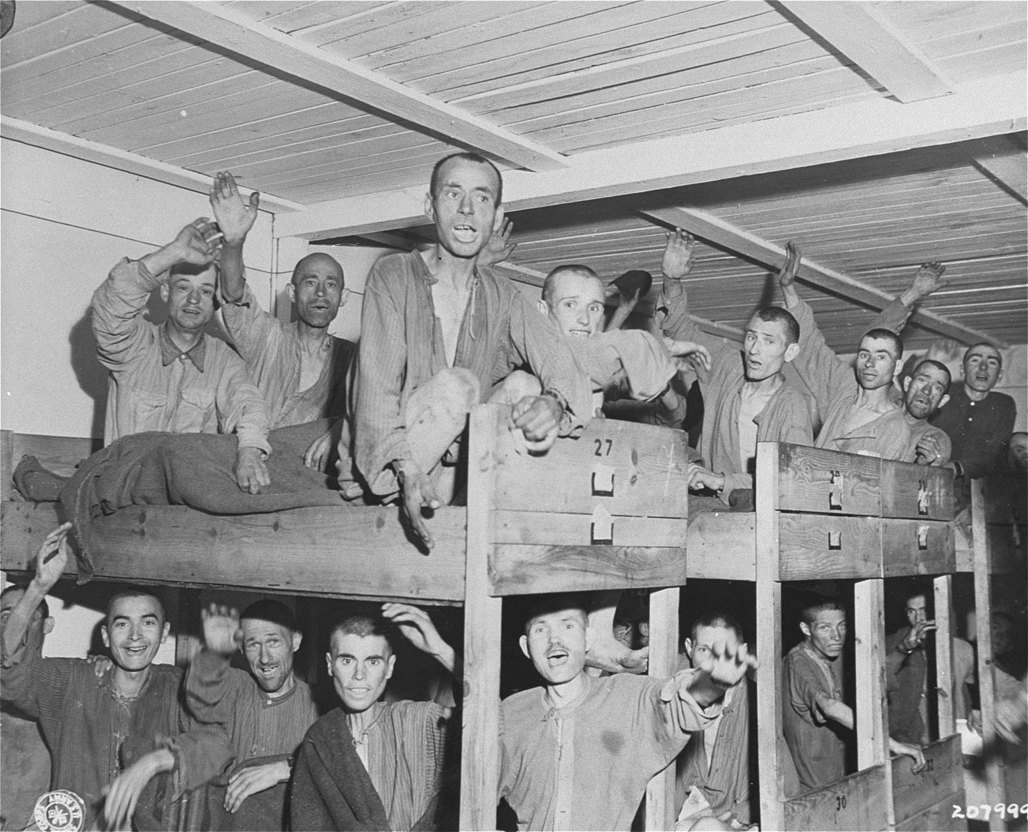 Survivors wave to American liberators from their bunks in the infirmary barracks for Jewish prisoners in the Ebensee concentration camp.

Among those pictured is Moshe Haelion (lower bunk, second from the right).