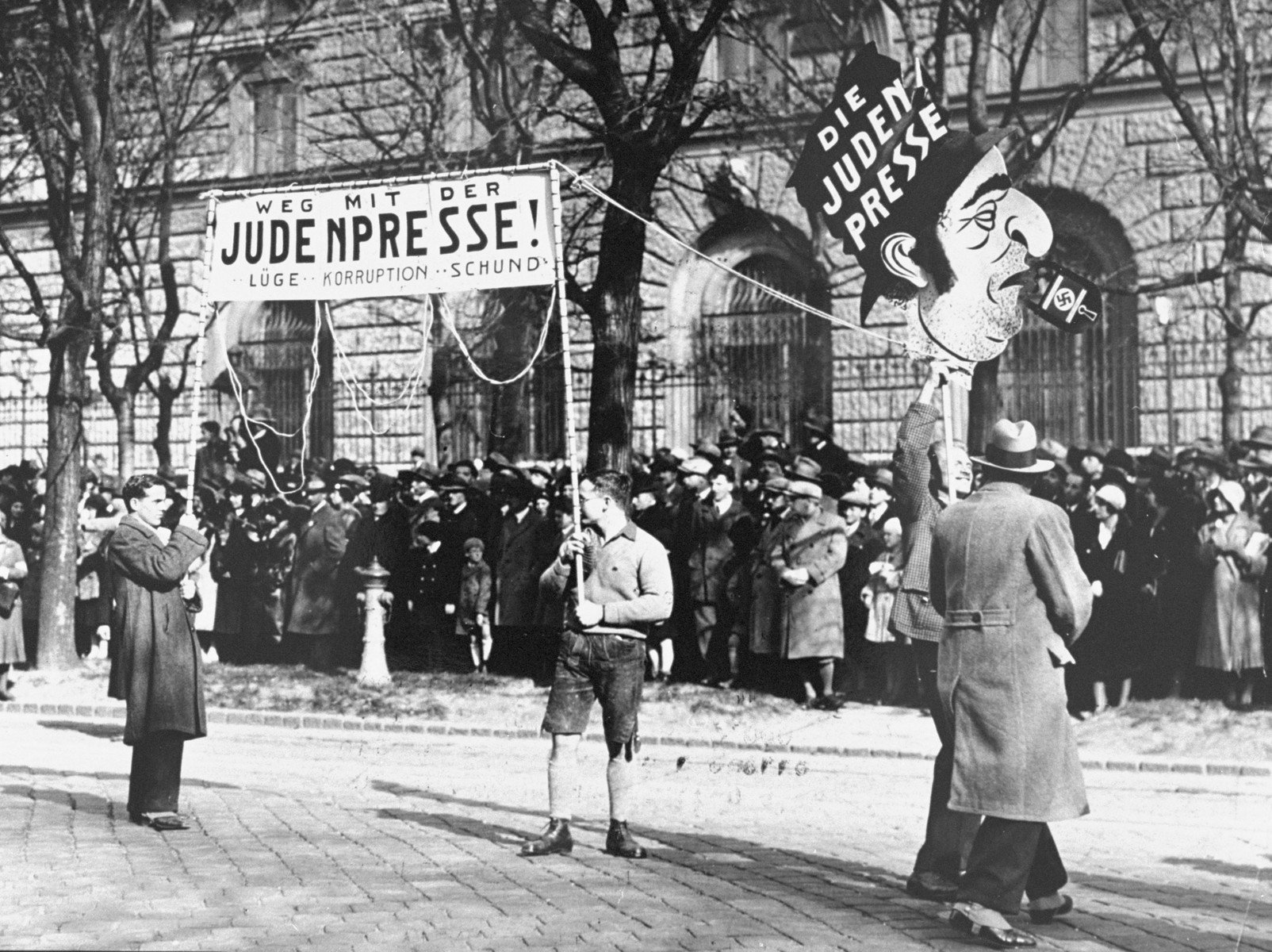 A large demonstration in Vienna in which 20,000 National-Socialists gathered on the Heldenplatz to protest against the St. Germain and Versailles treaties.  Demonstrators carry banners which read "Away with the Jewish press: lies, corruption, rubbish."
