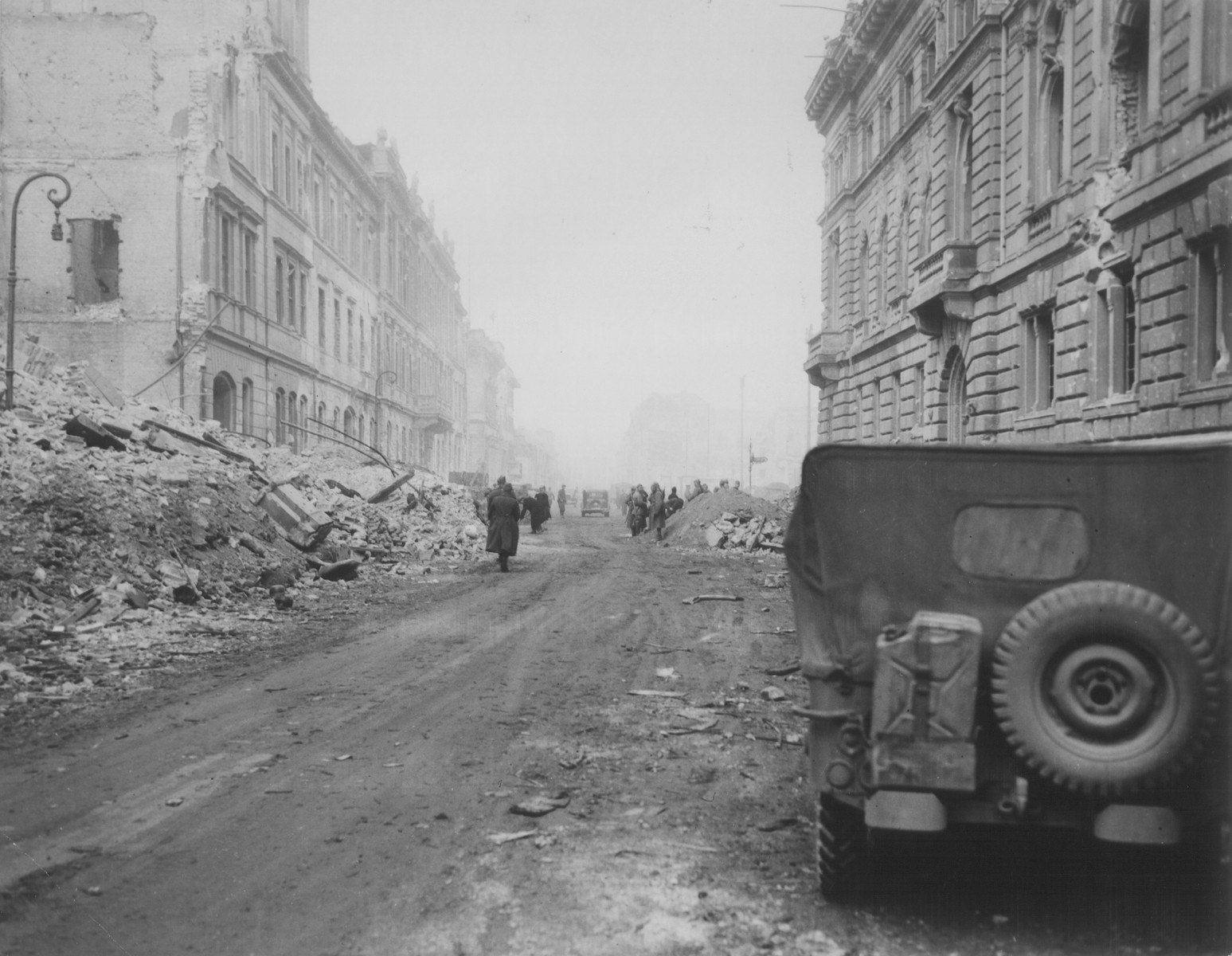 Allied troops walk along a rubble-strewn street in a German city at the end of World War II.