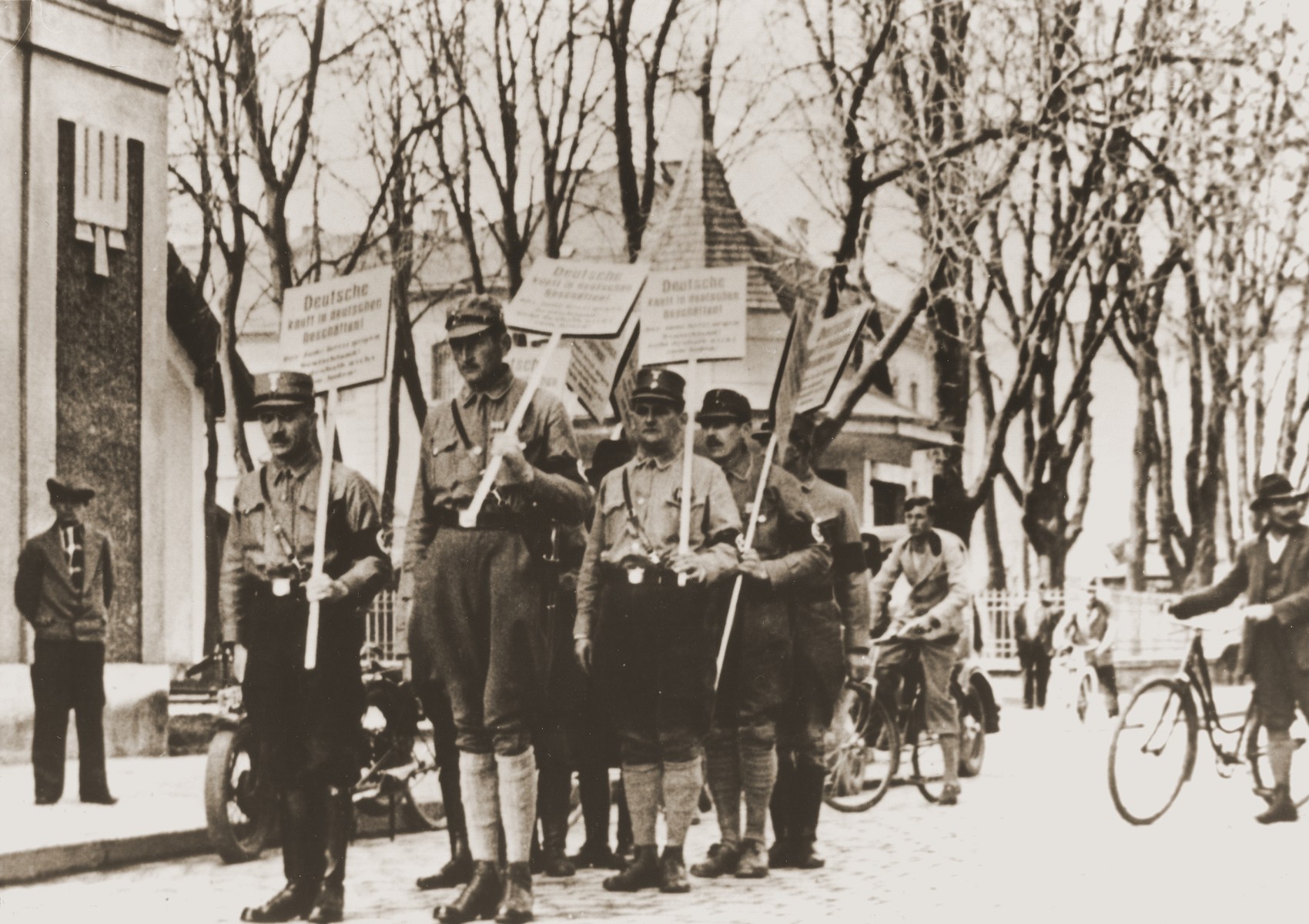 Members of the SA take to the streets of Rosenheim to enforce boycott of seven Jewish-owned businesses on the morning of April 1, 1933.  

Their signs read:  "Germans shop in German stores!  The Jew is stirring up hate against Germany!  Therefore, do not go to Jewish stores!"