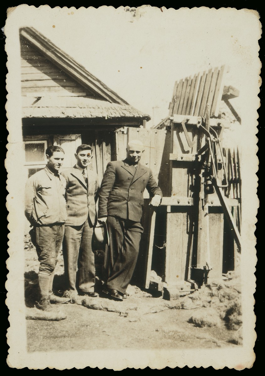 Mr. Derebiacki stands outside his linen factory with Pesach Avrahami and another youth.