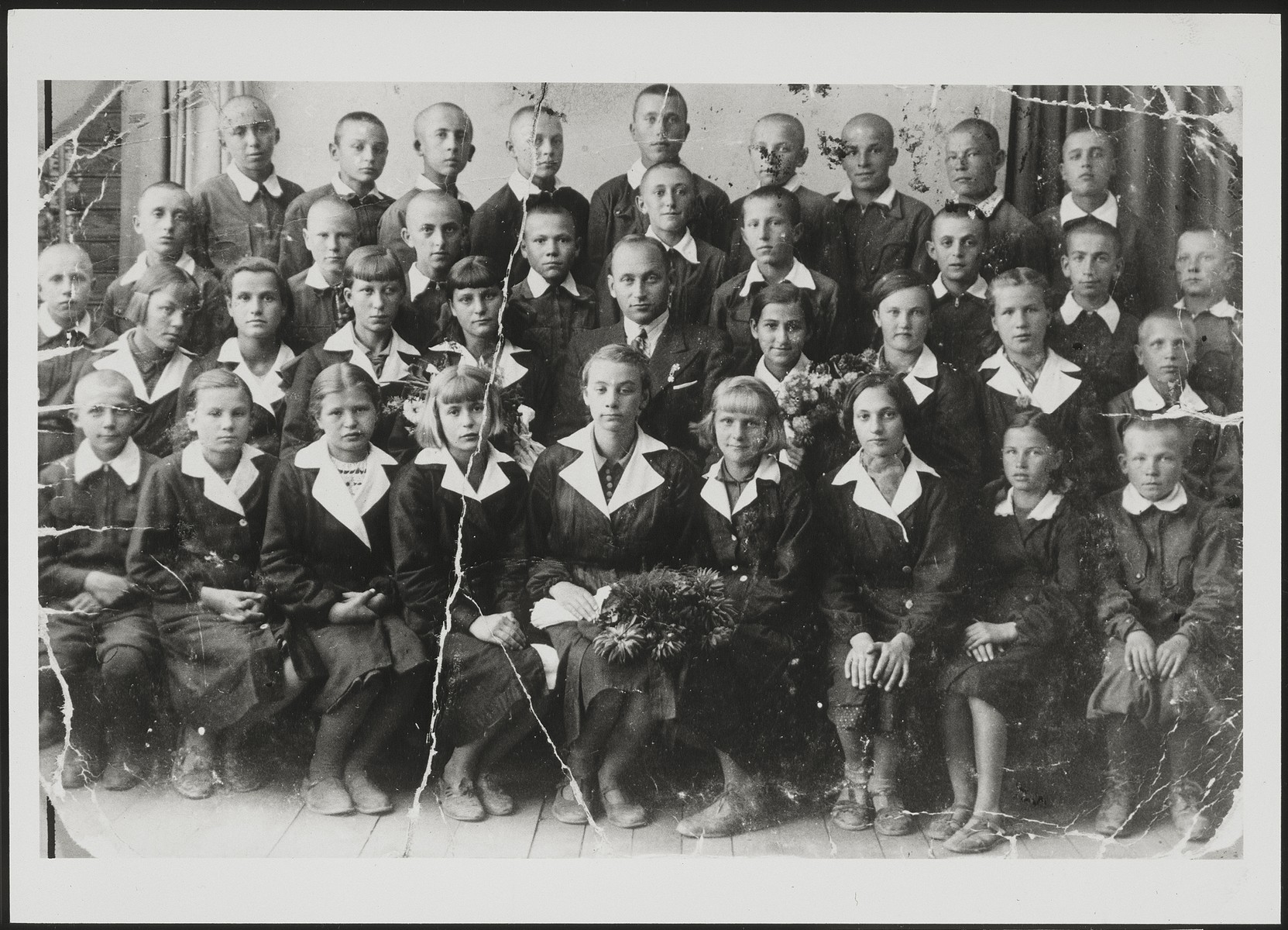 Polish and Jewish children in the Polish public school in Eisiskes. 

Second row from top: second from right is Shlomo Tevke Paikowski; third from right is Leon Kahn, fifth from right is Shmuel Sovitzky (behind the teacher). Third row from top: teacher Antonovicz is sitting in the center (he was a member of the Polish Home Army).  Hayya Levitan (second row from bottom, fourth from right) Front row, third from right is Menuha Michalowski. 

Leon Kahn survived the Holocaust. All the other Jewish children were murdered during the Holocaust.