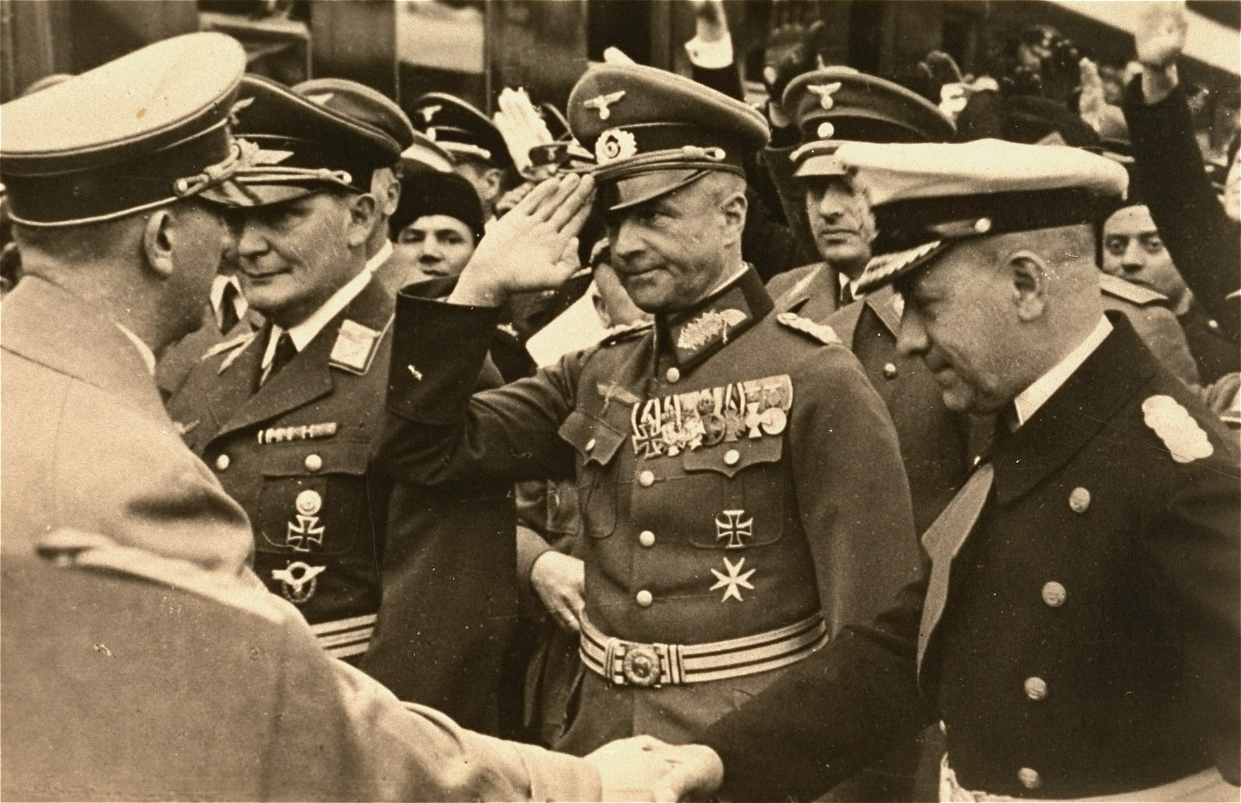 Hitler greets German military leaders at an official ceremony.  

Herman Goering stands at the left.