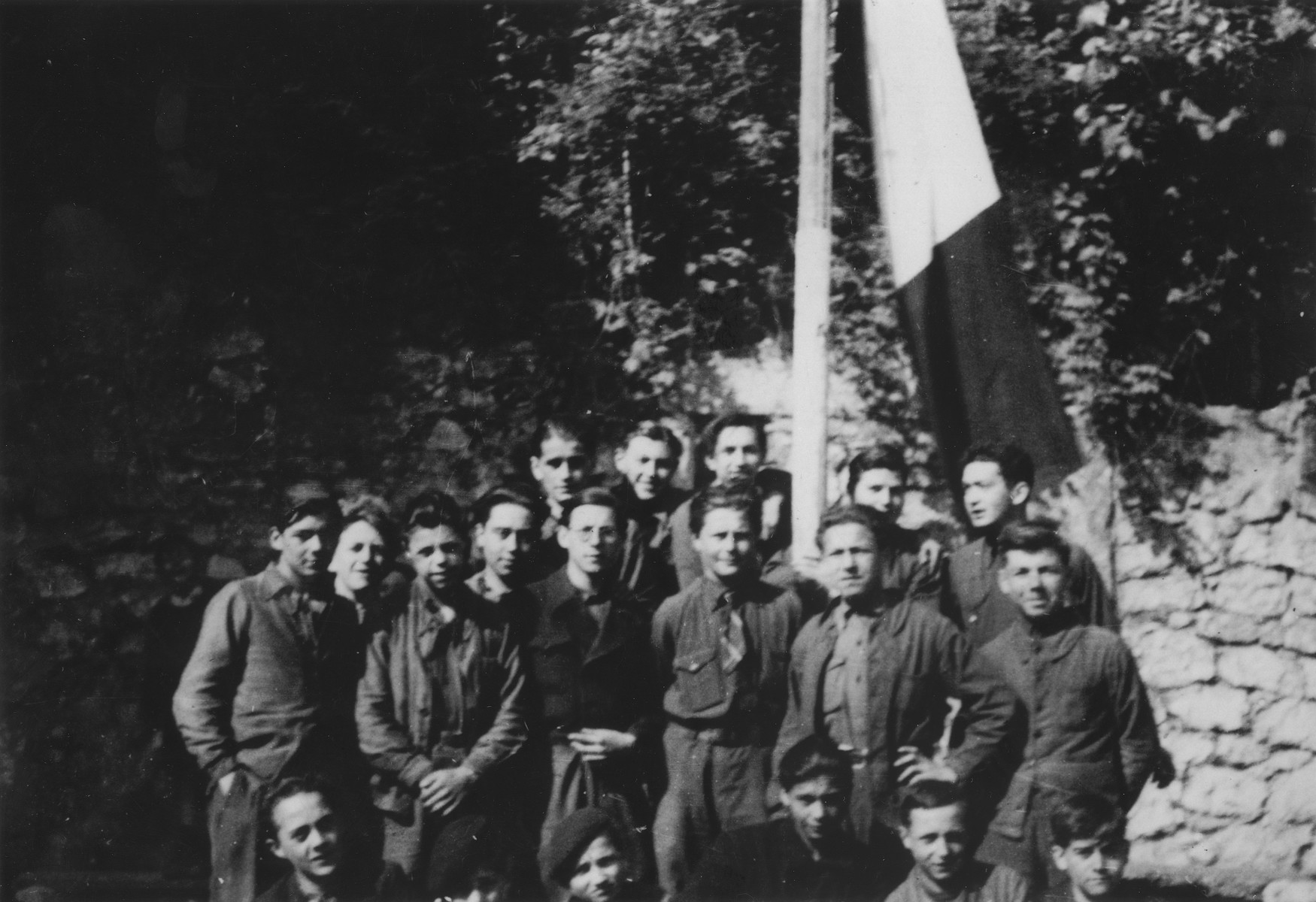 The members of the Vichy fascist youth movement, Moissons Nouvelles, gather around a flag pole in Pont de Beauvoisin.  A few of the boys are hidden Jews who were placed at the center by the OSE (Oeuvre de Secours aux Enfants).