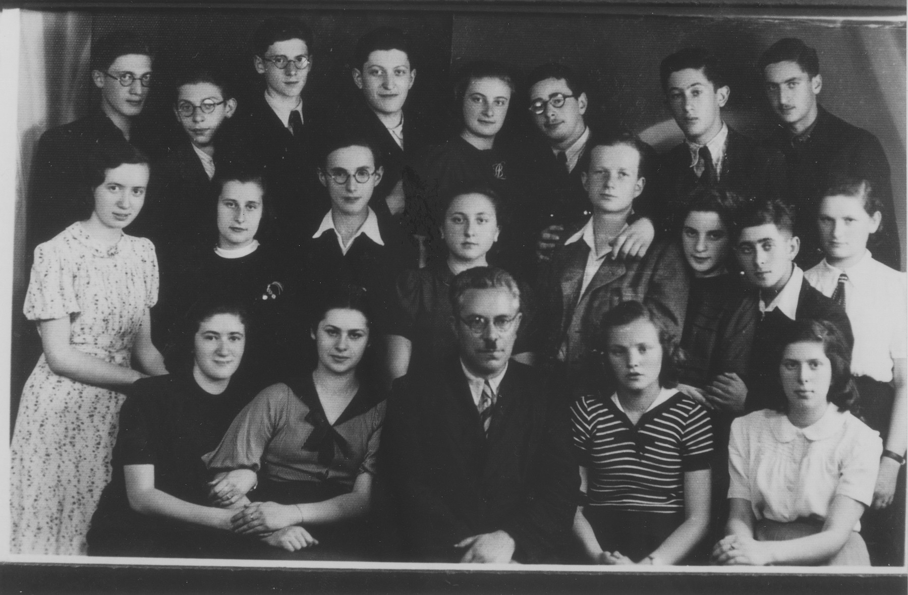 Prof. Elster poses with his students at the Furstenberg Gymnasium in Bedzin.

Seated in the front row, from left to right are: Lola Lustiger; Genia Szpigelman; Prof. Elster; Rozka Feder; Franka Grundman.  Second row: Renia Nunberg; Gucia Slowatycka; Mendek Rechnic; Sala Goldberg; Heniek Blumenfrucht; Bela Ehrlich; Izio Koenigsberg; Golda Grynberg.
Third row: Izak Blumenkranc; Natek Buchner; Samek Zelinger; Zabner; Lola Brodkiewicz; Moniek Teitelbaum; unknown; and Jerzyk Mandelkern.