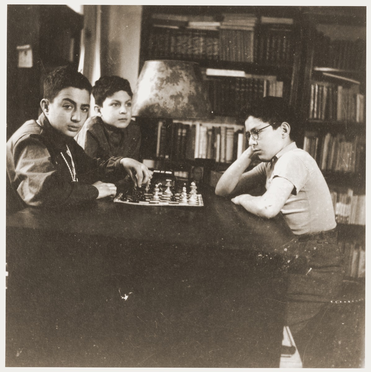 Amos and Binyamin Rabinovitch playing chess in the family house on Gedimino Street.  Their younger brother Shmuel looks on.