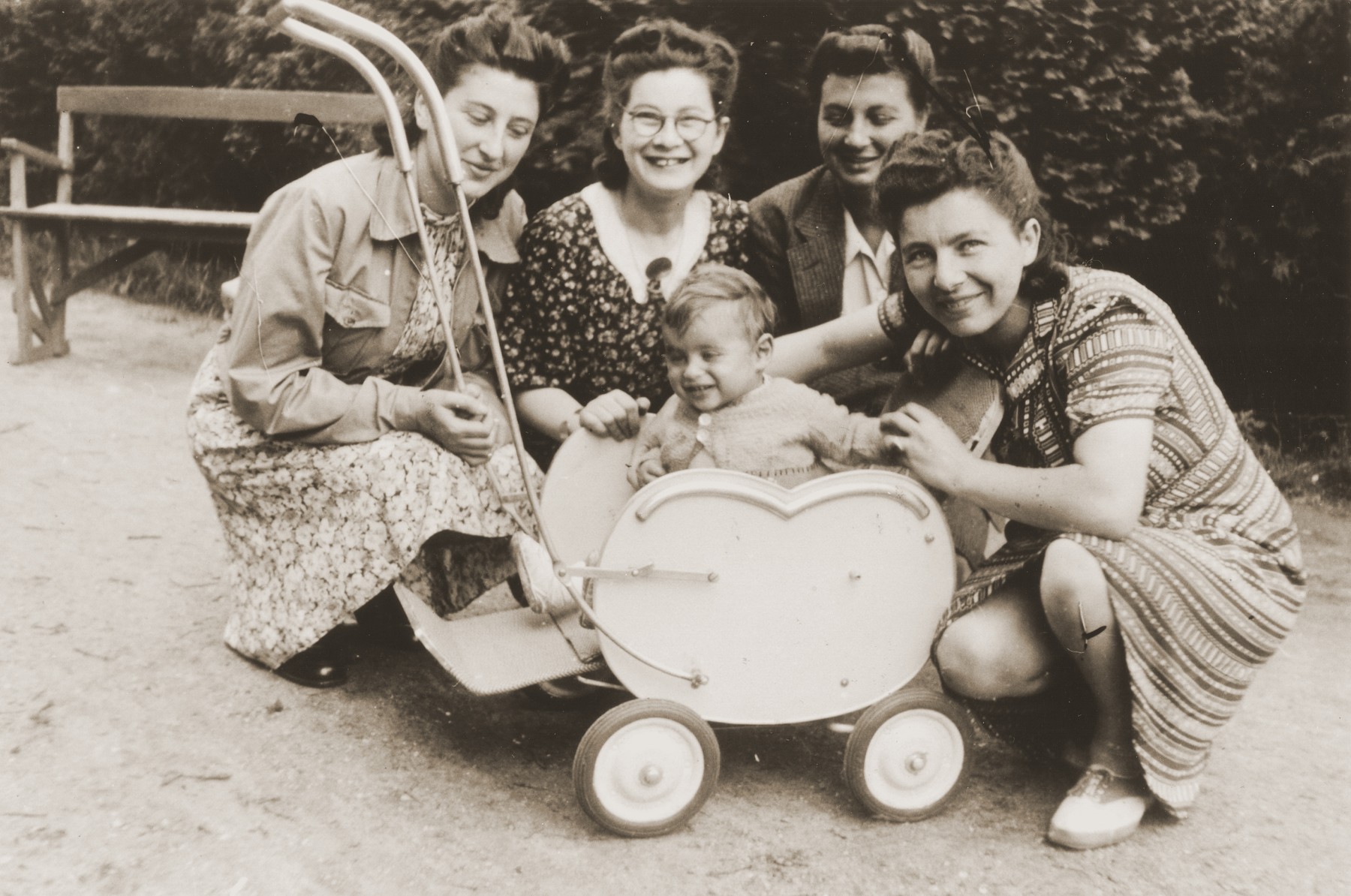 A young Jewish child sits in a stroller in a park surrounded by his mother (right) and three aunts.

Pictured is the toddler, Rene Gruneberg; his mother, Bertha Gruneberg; and his aunts (left to right): Bep Meyer; Bettie Meijer, and Renee (Sara) Meijer.  The child survived the war, but both his parents were killed.