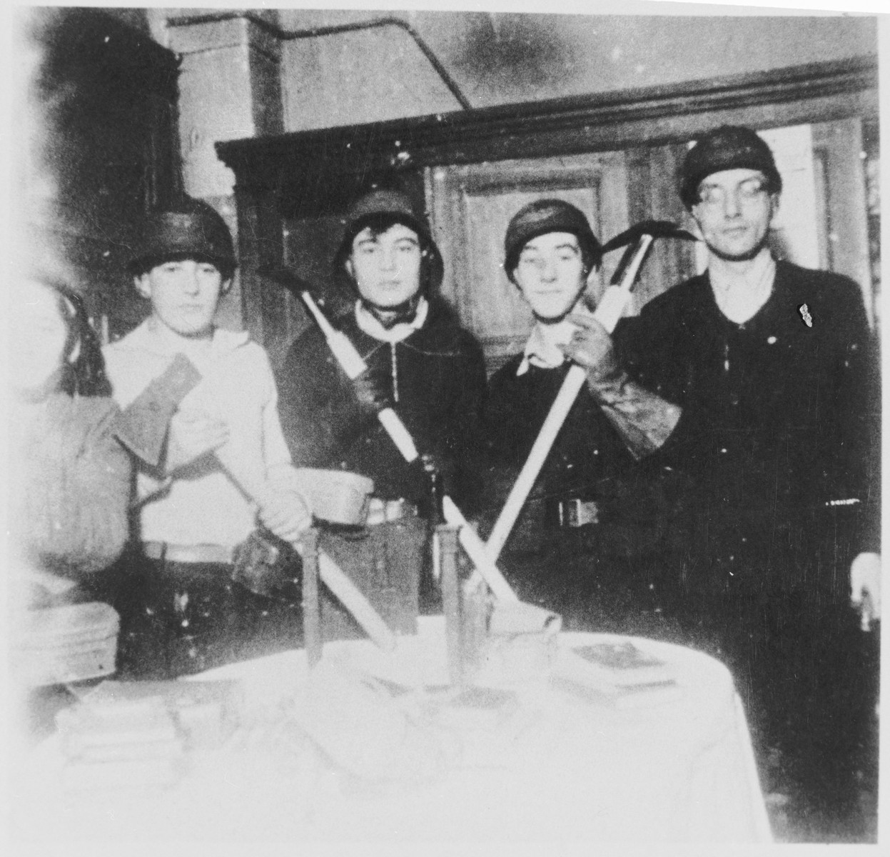 Students and teachers at the Youth Aliyah school in Berlin pose with helmets and tools during a mandatory air raid patrol shift.  

Pictured on the far right is the director of the school, Jizchak Schwersenz.