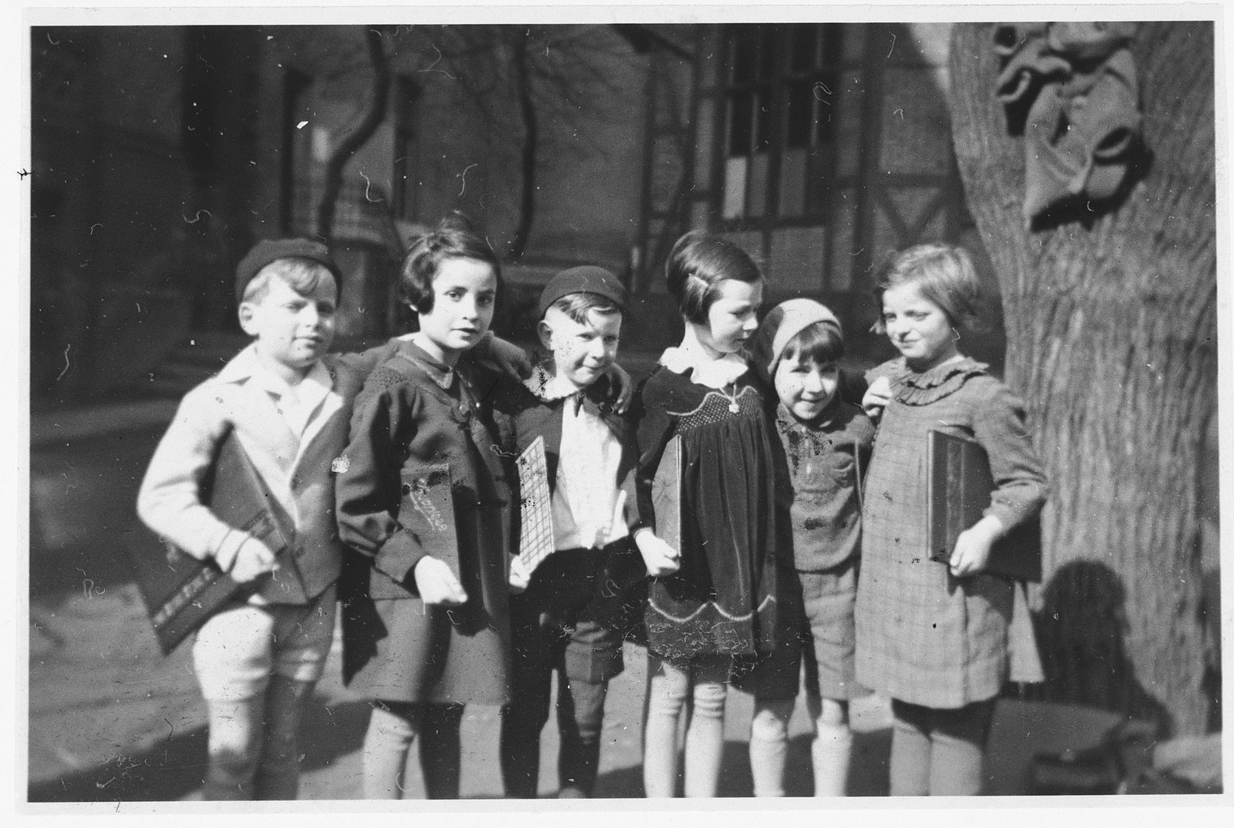 Six school friends pose in a row with their report cards after completing first-grade. 

Those pictured include Hannelore Mansbacher (first from right), Heinz Kleczewski (second from right) and Hanna Frischer (second from left). Only Hannelore Mansbacher survived the war.