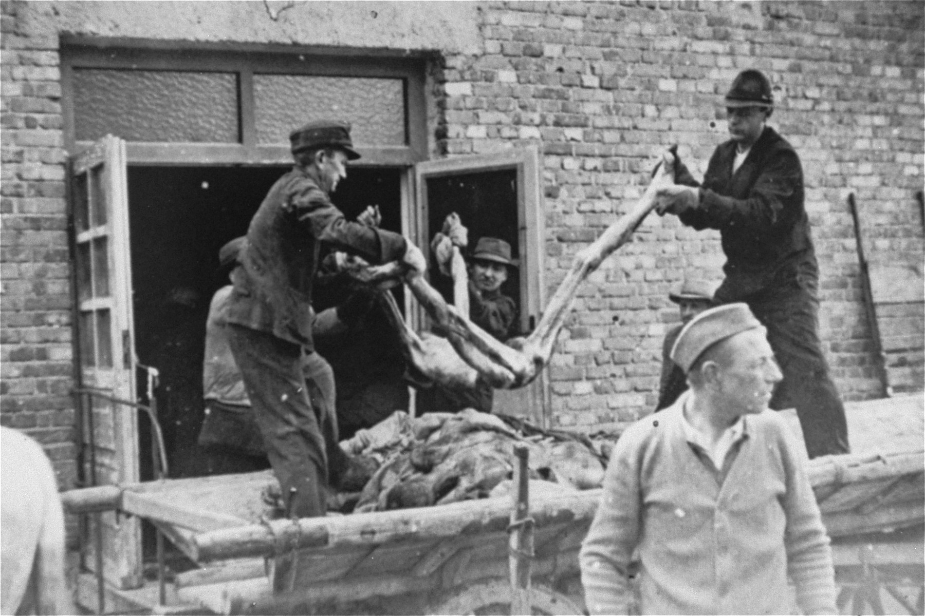 German civilians remove corpses from the crematoruim mortuary for transport to nearby burial sites where they will be interred in mass graves.