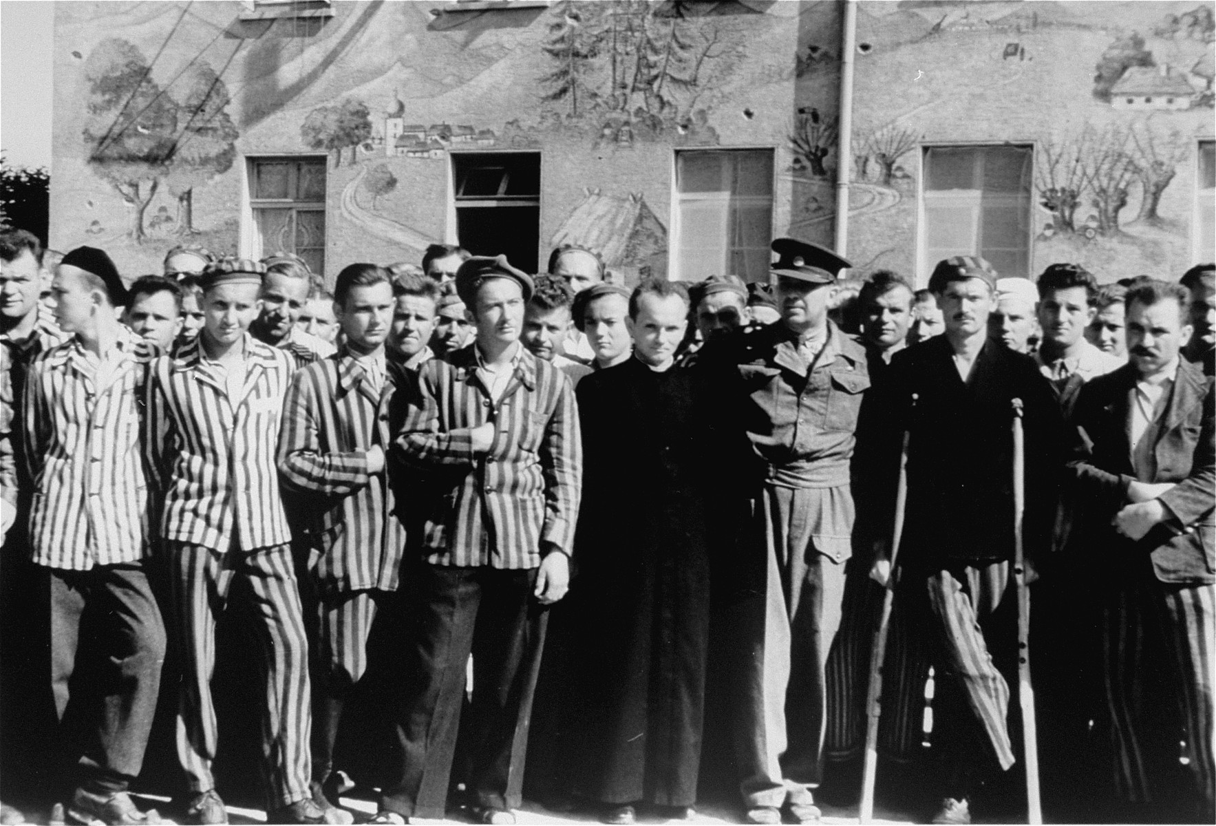 Major Edminson of UNRRA in Dachau with survivors his agency is aiding.  The priest next to him is a Pole and is one of the 150 survivors of 2500 Polish Roman Catholic priests who were incarcerated in Dachau.