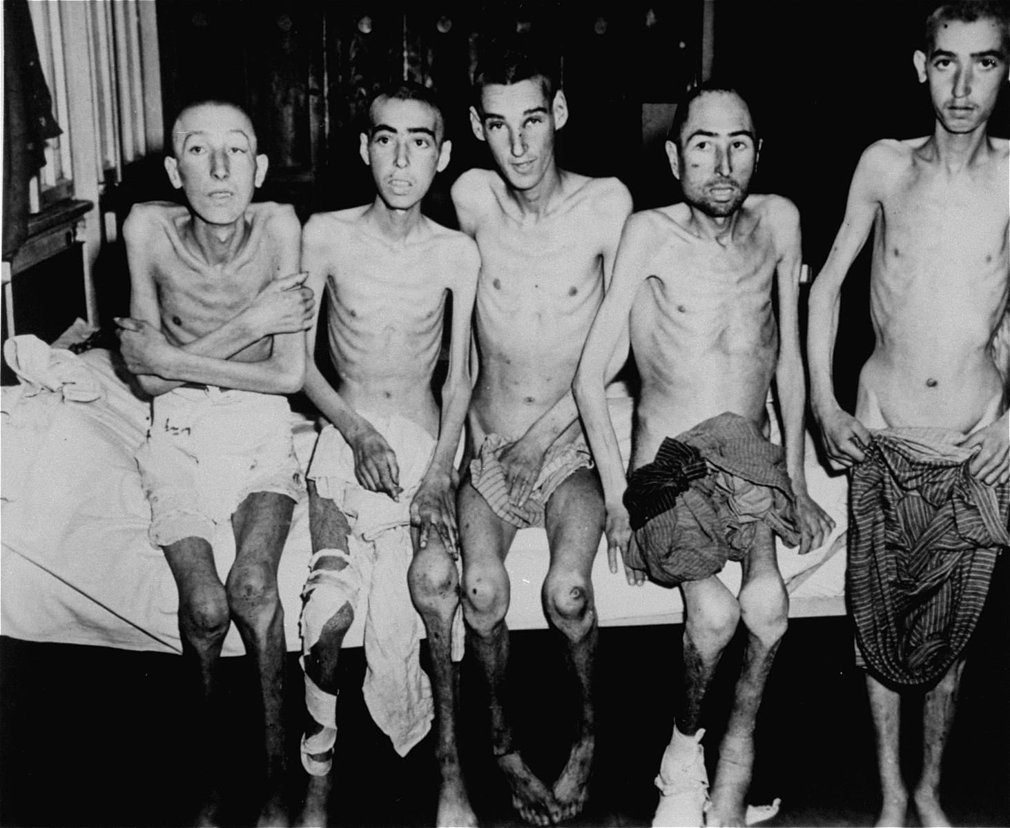 Group portrait of emaciated survivors in the infirmary of the Dachau concentration camp soon after the liberation.