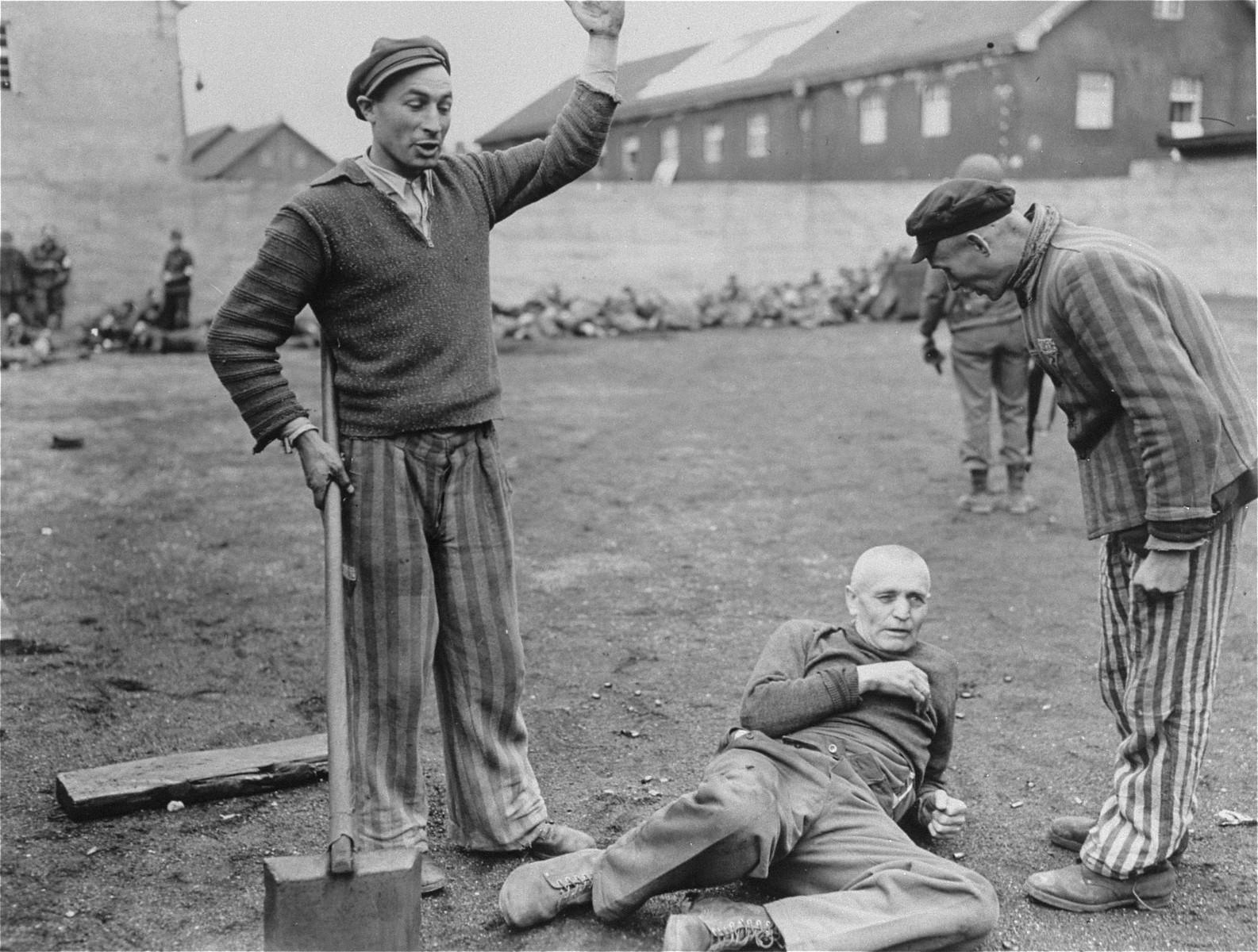 Survivors in Dachau berate an SS guard captured by U.S. troops, while in the background American soldiers summarily execute other camp guards.